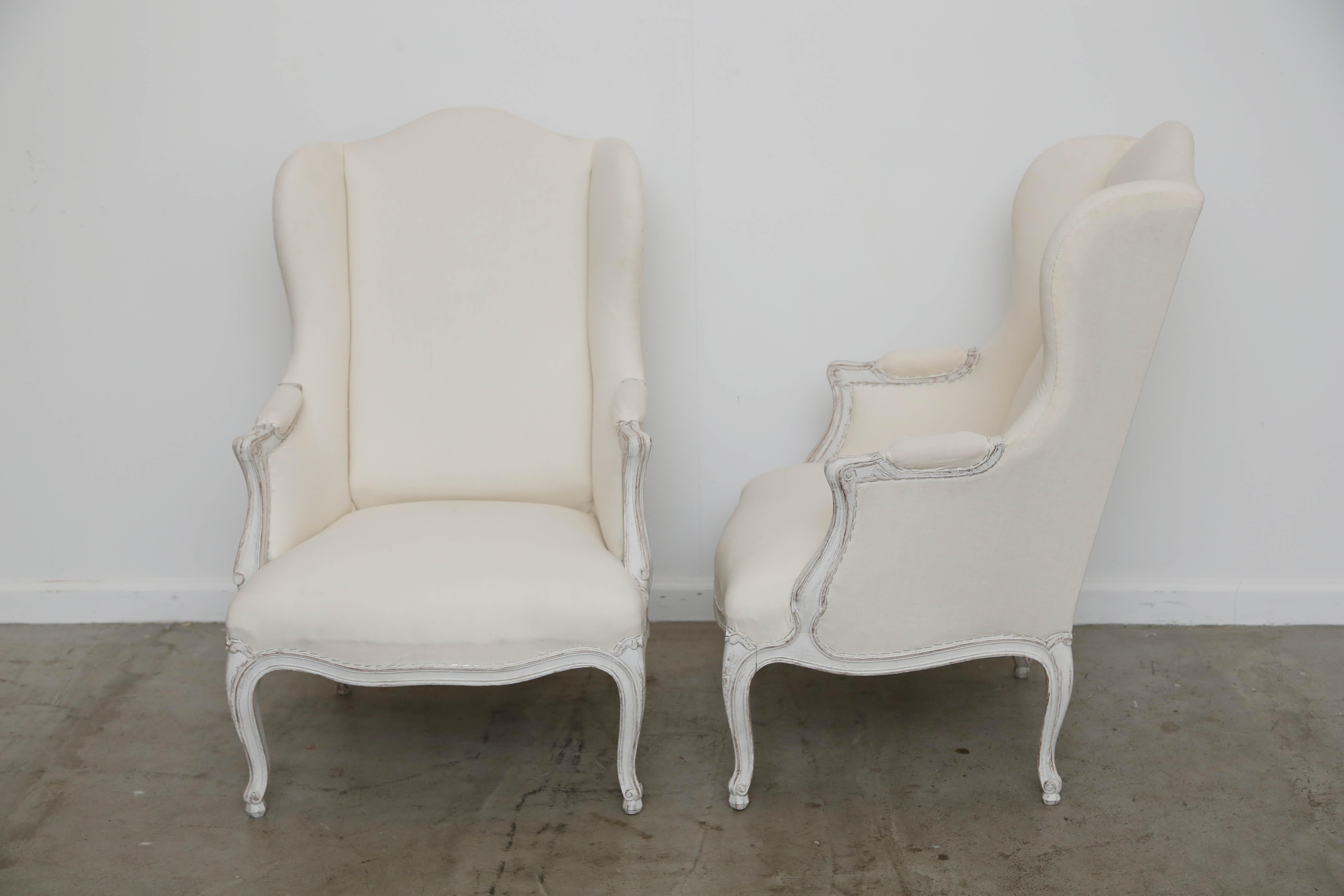 Pair of antique Swedish Rocco style wing chairs with painted wood carved arms and bottom apron and legs. The chairs are a smaller scale frame with lovely proportions. The arms are part padded and carved at the ends, bottom is curve shaped and