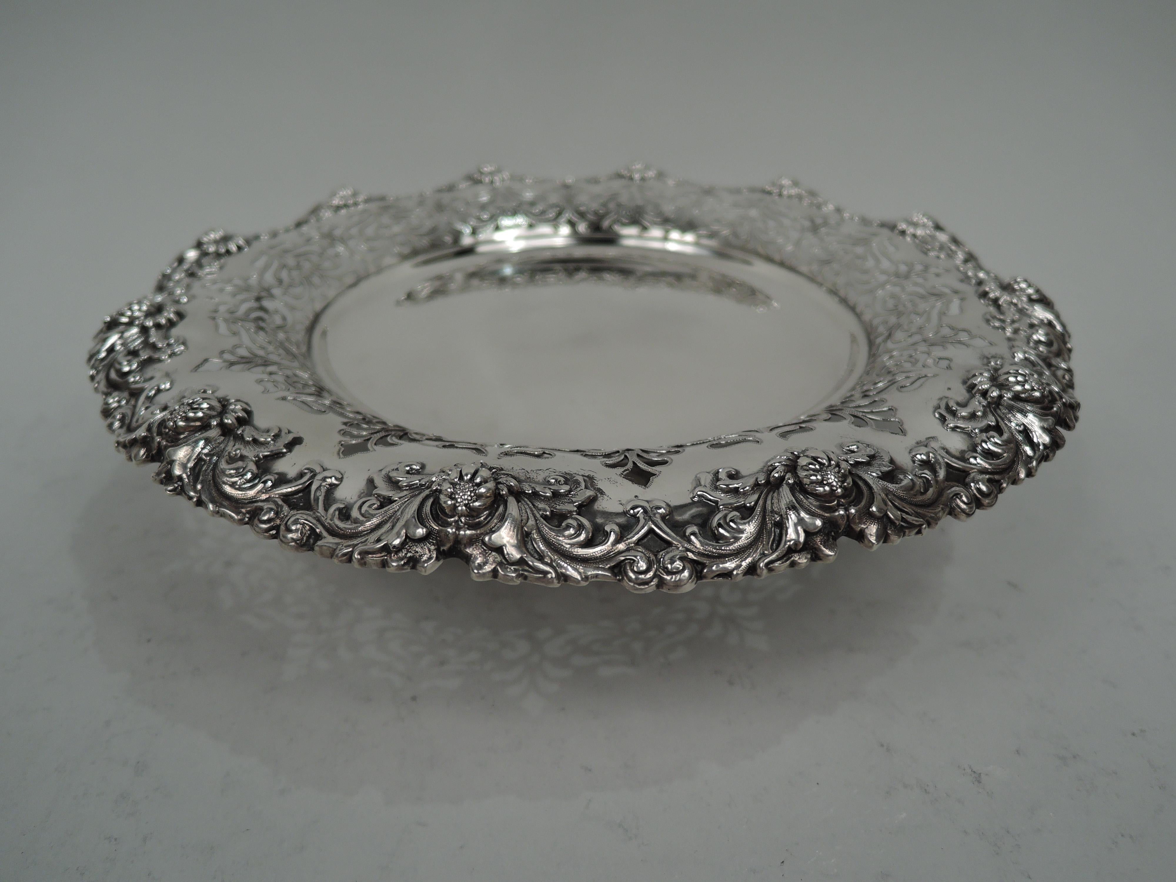 Pair of Victorian Classical sterling silver compotes. Made by Tiffany & Co. in New York. Each: Round solid well and concave sides with pierced leafing scrollwork; raised foot. Rims have applied leafing scrollwork and buds that suggest the influence