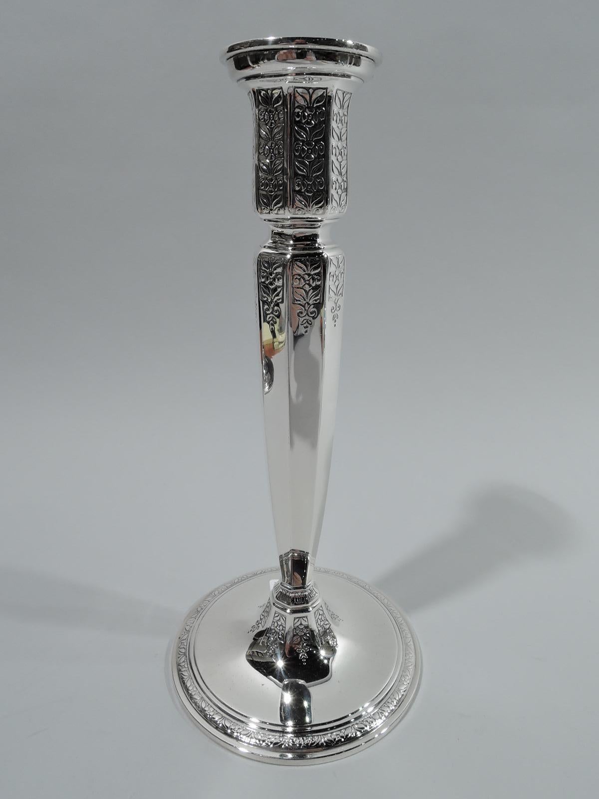 Pair of Art Deco sterling silver candlesticks. Made by Tiffany & Co. in New York, ca 1924. Each: tapering and faceted shaft mounted to raised and banded circular foot. Shaft top inset and surmounted by straight and faceted socket. Detachable