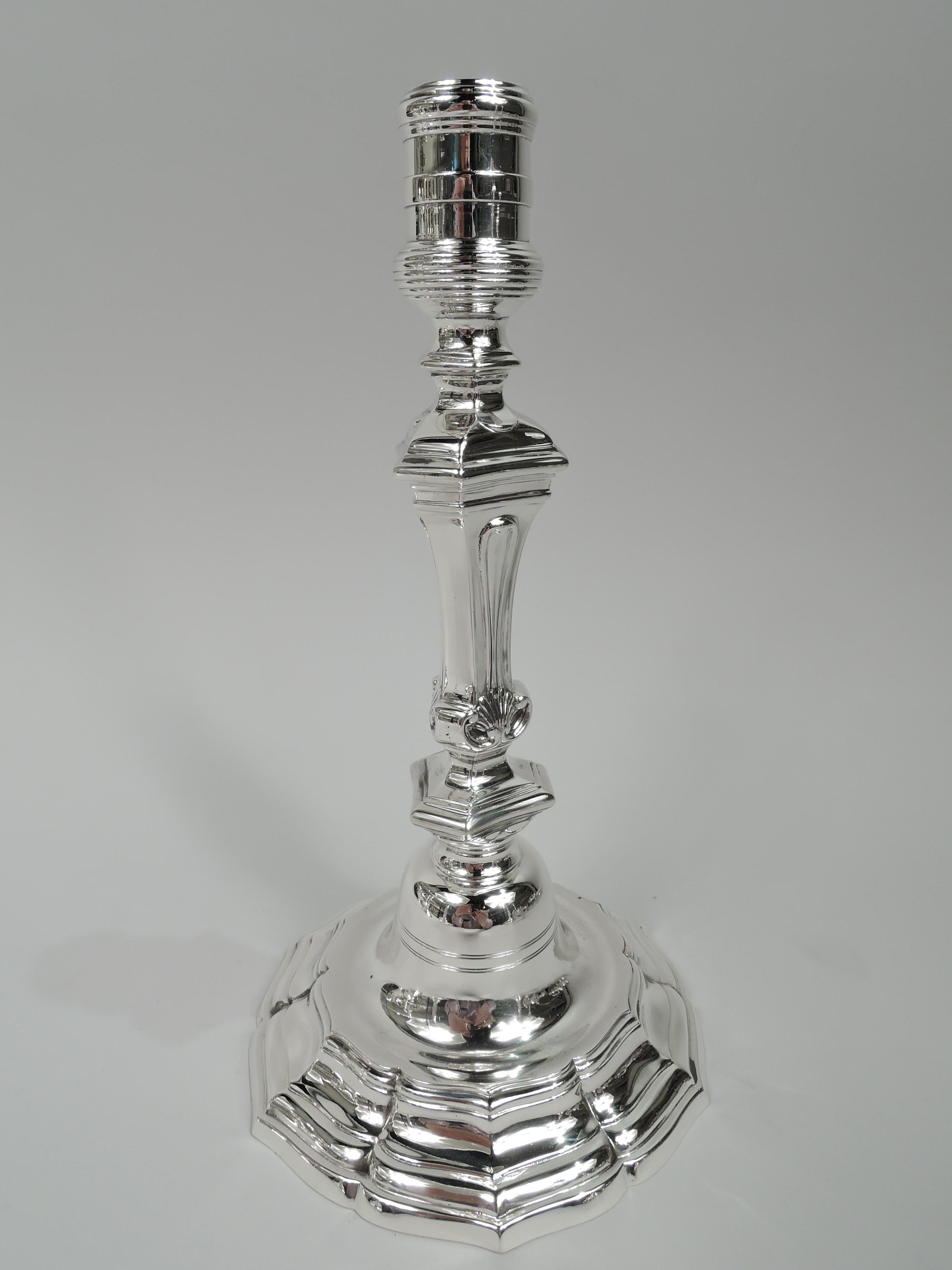 Pair of Baroque-style sterling silver candlesticks. Made by Tiffany & Co. in New York, ca 1916. Each: Reeded and bellied socket on tapering and chamfered shaft. Foot domed in round and concave base with ogee rim. Faceted. Scallop shells and engraved