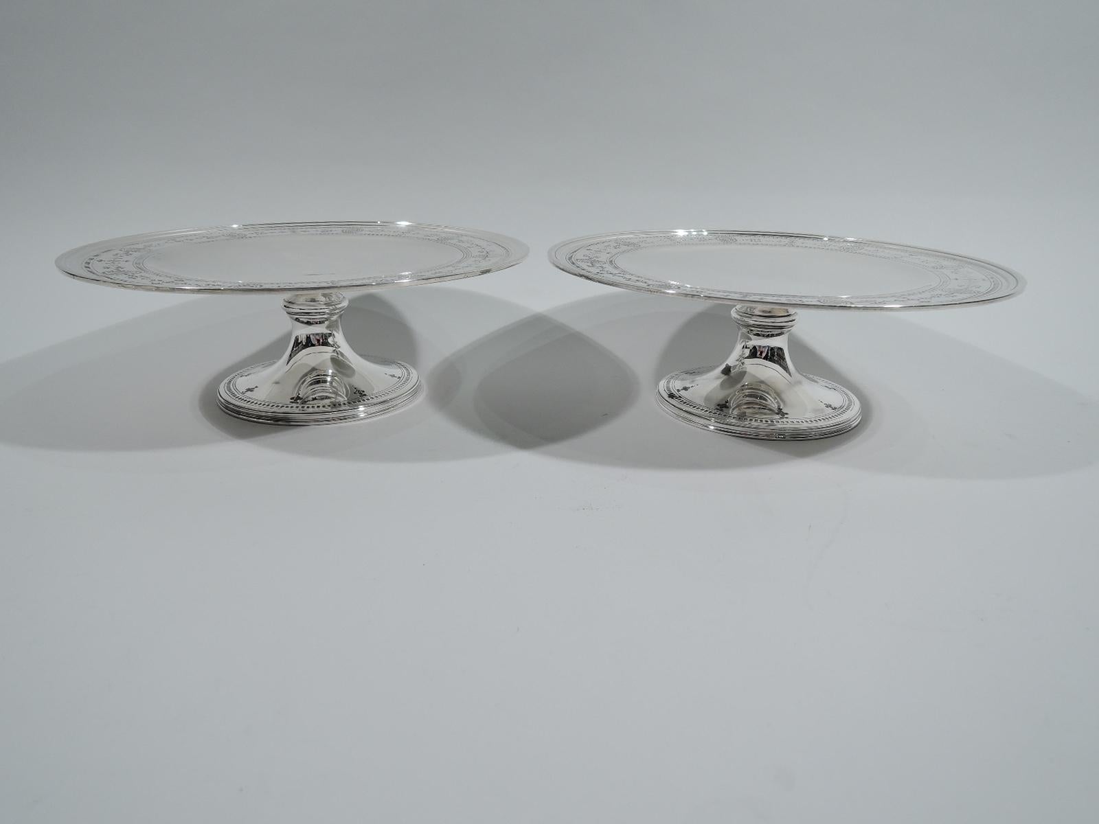 Pair of Edwardian Regency sterling silver compotes. Made by Tiffany & Co. in New York, ca 1927. Round and shallow well. Wide shoulder engraved with Neoclassical border, including beaded oval medallions inset with covered vases, between dentil