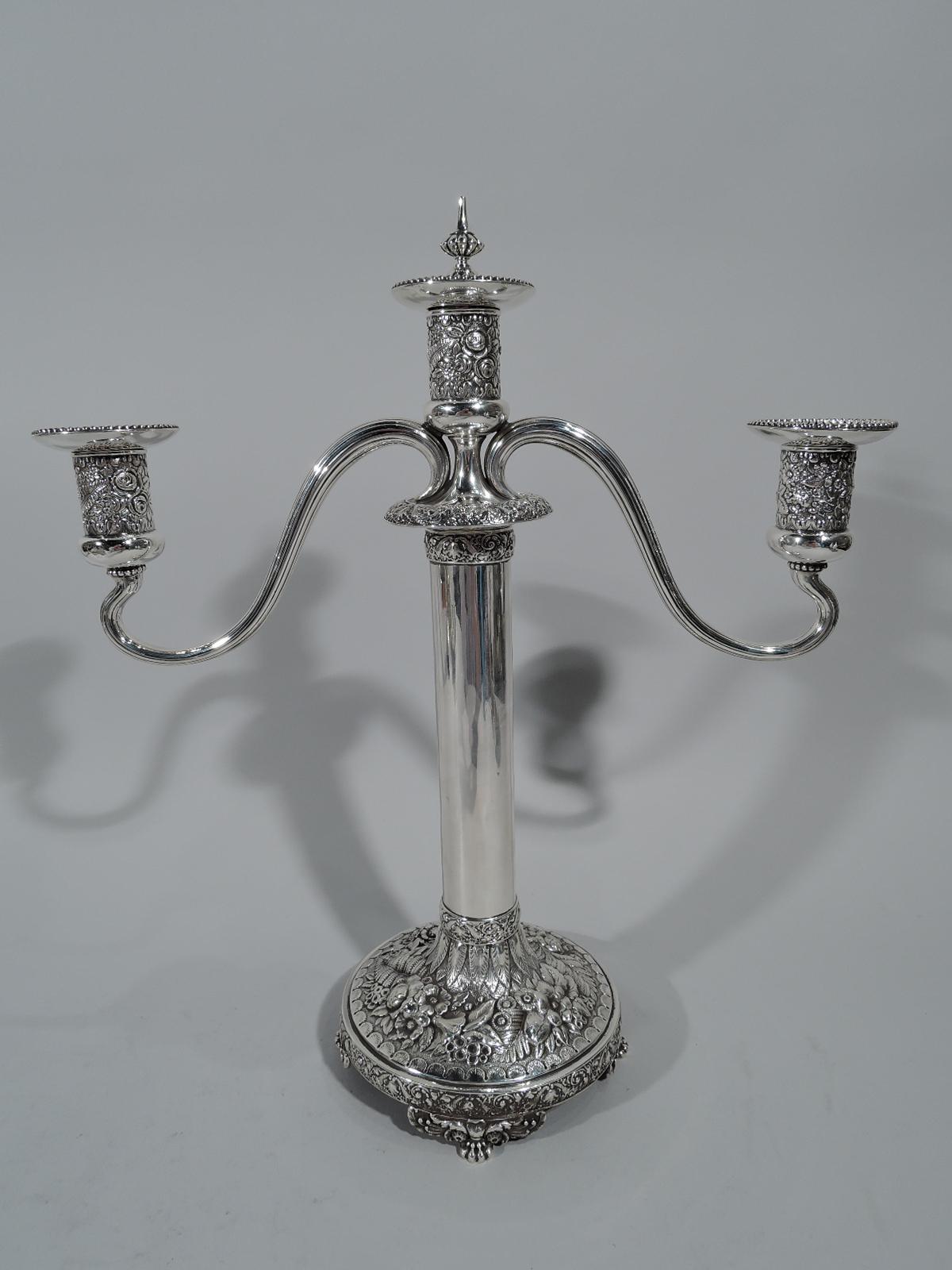 Pair of sterling silver three-light candelabra. Made by Tiffany & Co. in New York. Each: Plain columnar shaft on domed foot supported by 4 leaf-mounted paws. Two reeded s-scroll arms, each terminating in single socket and mounted to central socket