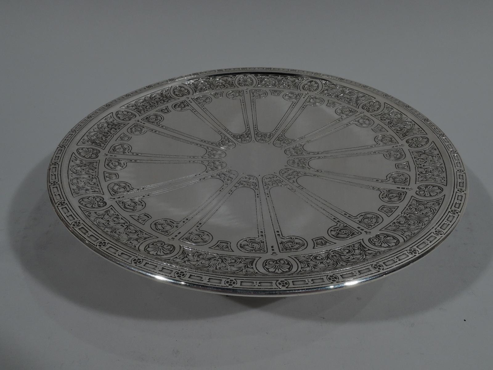 Pair of classical sterling silver compotes. Each: Round plate on raised and spread foot. Acid-etched ornament: Vacant center radiating V-Form frames with volute scroll terminals, in turn, bordered by alternating scallop shells and leafy scrolls. Rim
