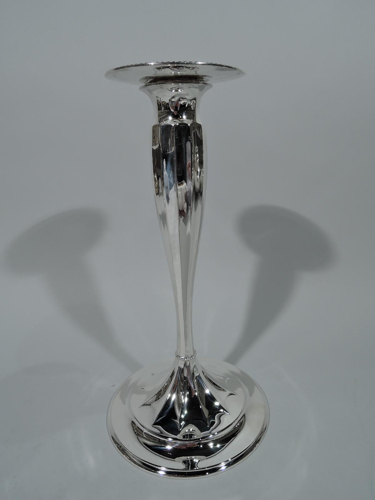 Pair of sterling silver candlesticks. Made by Tiffany & Co. in New York. Each: Fluted tapering shaft terminating in raised and fluted star on round and raised foot. Beaded knop at base. Detachable bobeche same. Hallmark includes pattern no. 12221