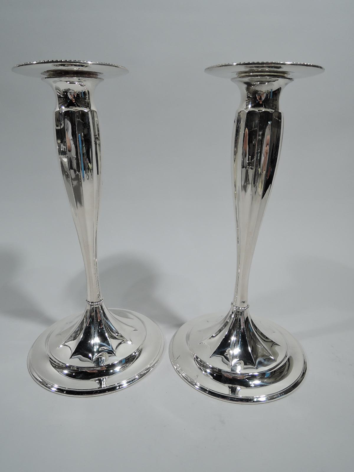 Pair of sterling silver candlesticks. Made by Tiffany & Co. in New York. Each: Fluted tapering shaft terminating in raised and fluted star on round and raised foot. Beaded knop at base. Detachable bobeche same. Hallmark includes pattern no. 12221