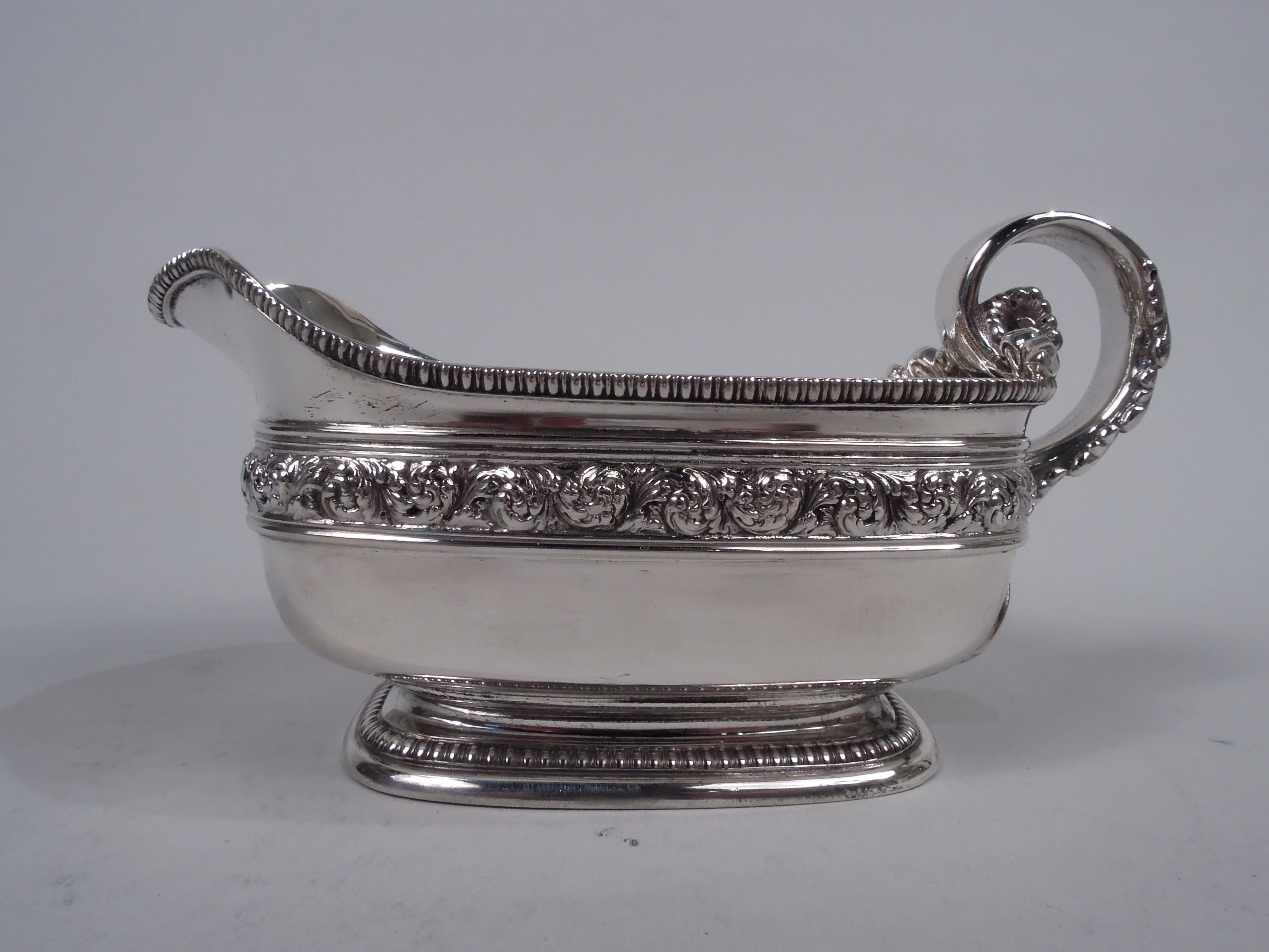 Pair of Victorian Classical sterling silver sauceboats. Made by Tiffany & Co. in New York, ca 1883. Each: Rectilinear body with lip spout and curved corners on same raised foot; high-looping leaf-covered handle with ribbed cast volute scroll
