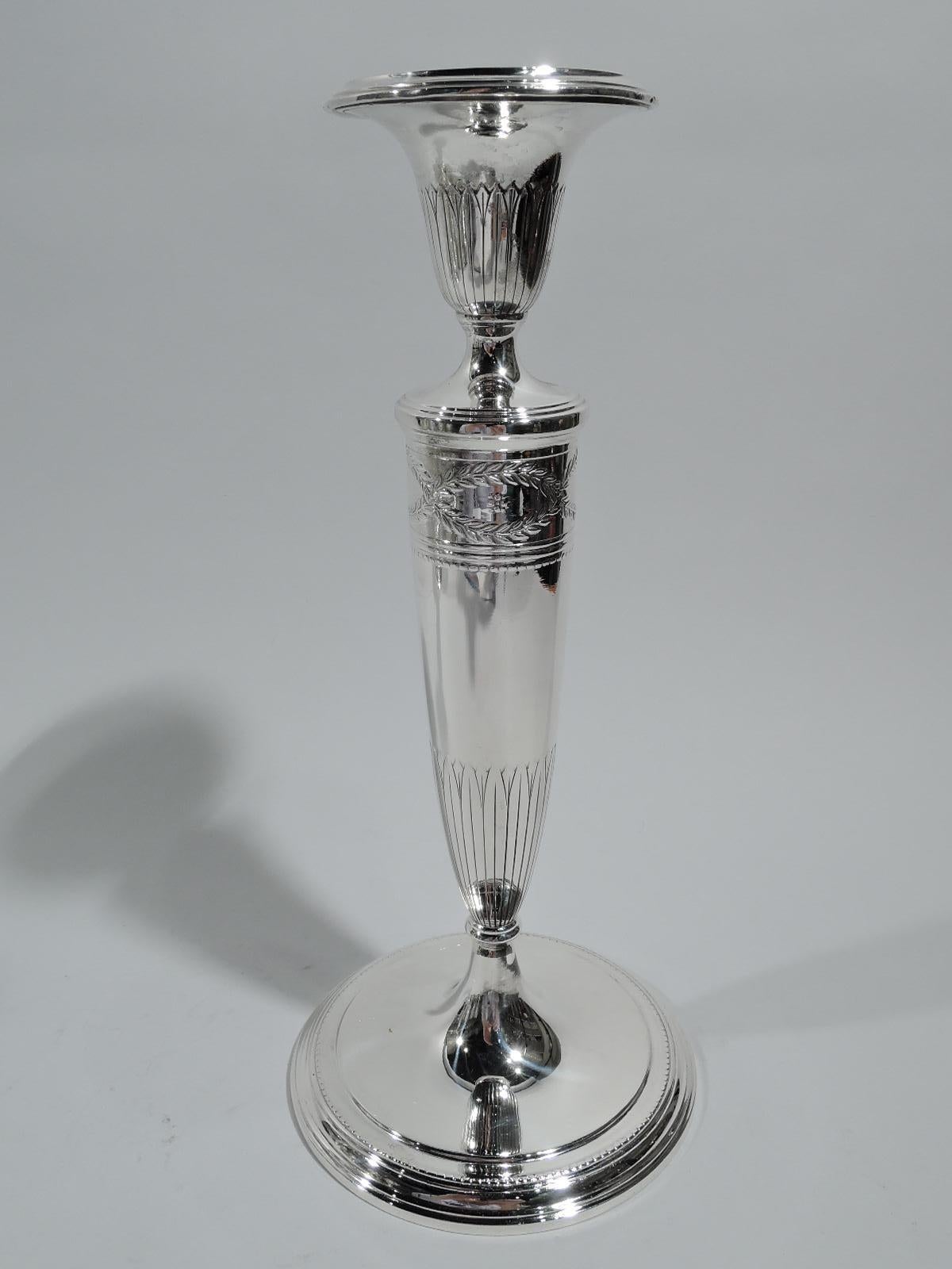 Pair of Winthrop sterling silver candlesticks. Made by Tiffany & Co. in New York, ca 1922. Each: Tapering columnar shaft on raised foot. Urn socket with detachable bobeche. Shaft top has the Classic laurel-wreath border inset with flower heads. Urn