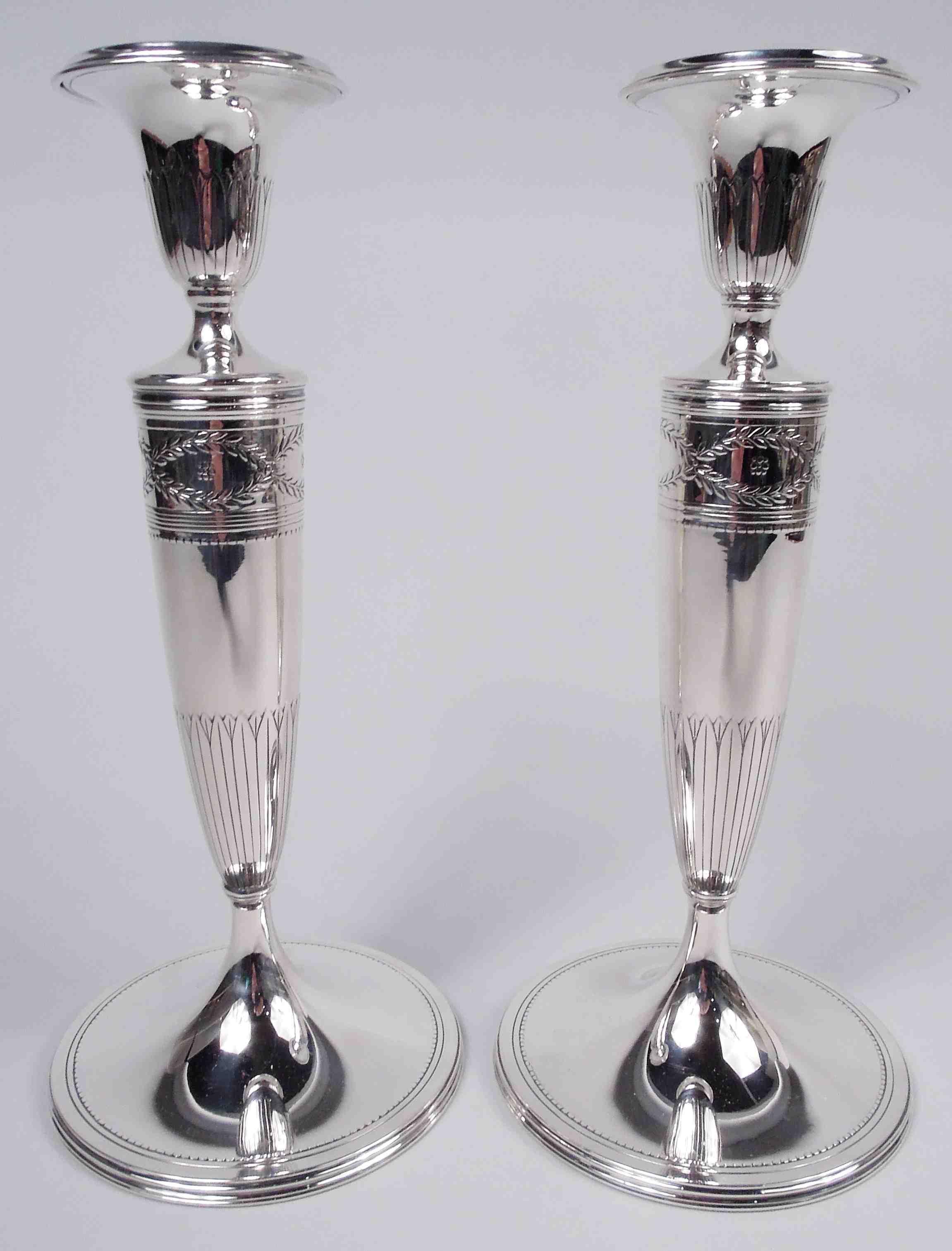 Pair of Winthrop sterling silver candlesticks. Made by Tiffany & Co. in New York, ca 1911. Each: Tapering columnar shaft on raised foot. Acid-etched ornament. Urn socket with detachable bobeche. Shaft top has the classic laurel-wreath border inset