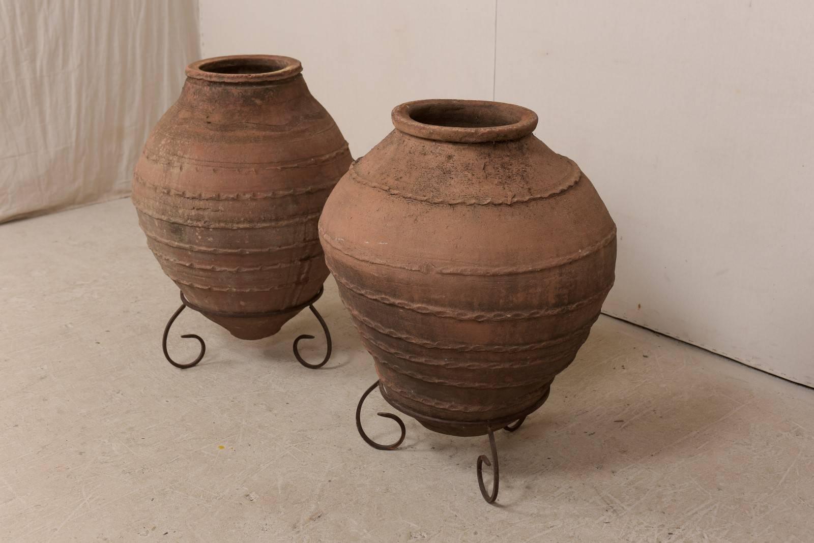Patinated Pair of Antique Turkish Olive Jars Made of Terracotta on Scrolled Metal Stands
