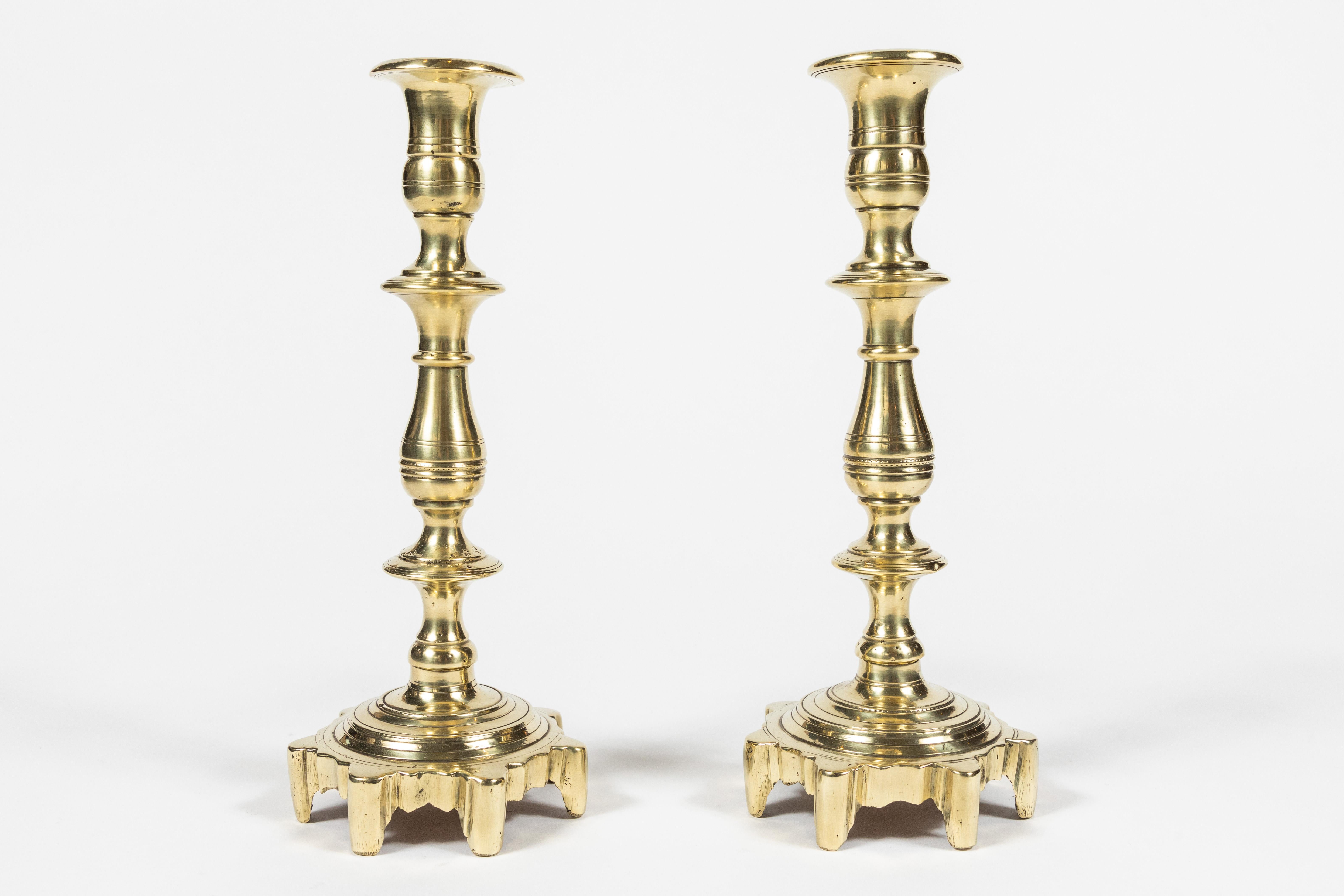 Pair of antique turned stem and multi foot base brass candlestick.