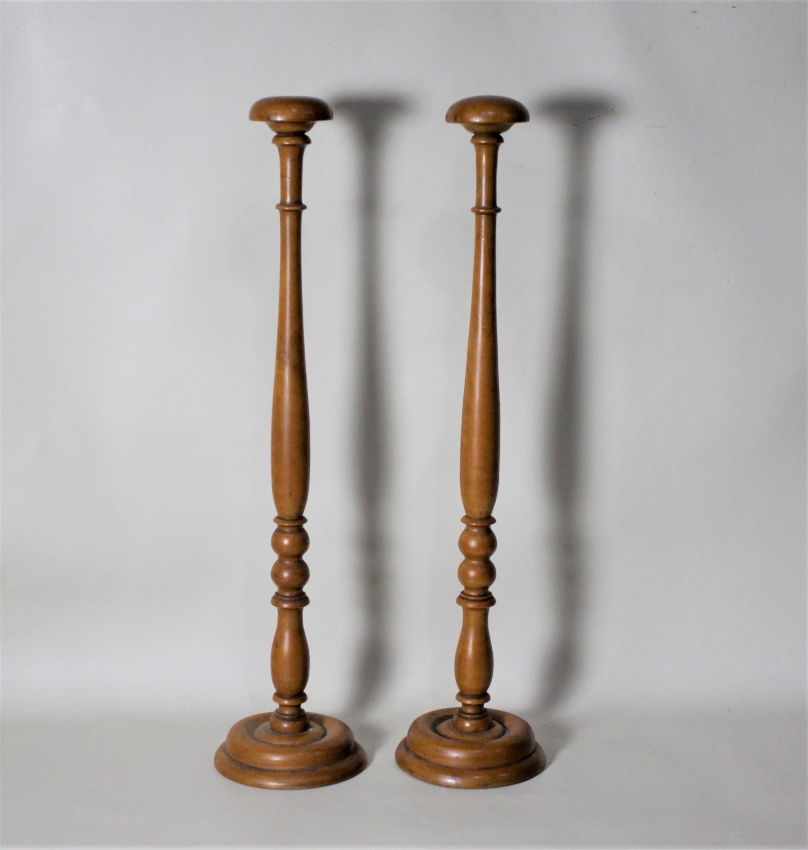 This antique pair of turned wooden hat stands show no maker's marks, but presumed to have been made in the United States in a Federalist style. Each of the two posts of these stands is mounted on a turned wooden base. The stands are stamped with