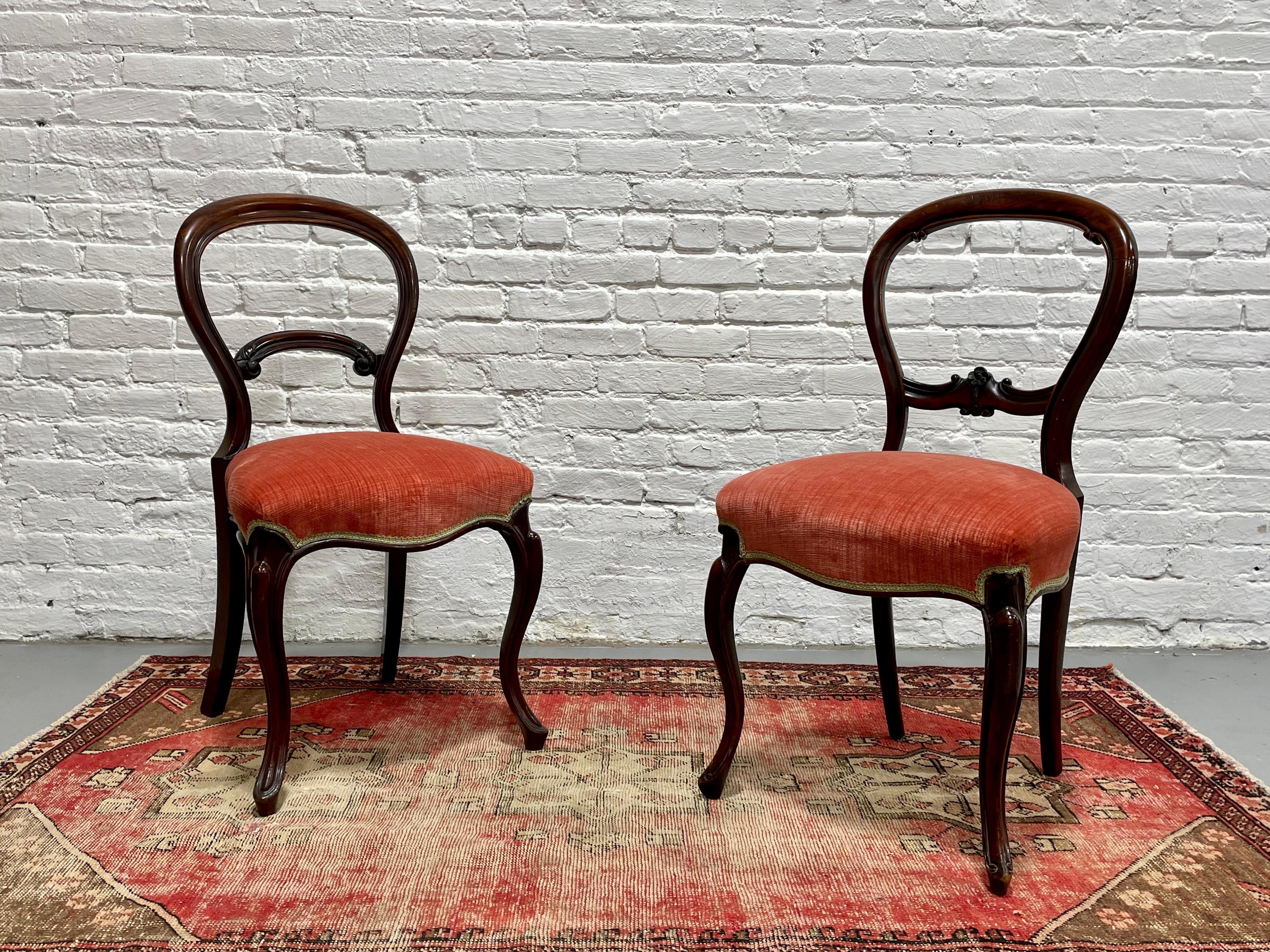 Pair of Antique Solid Mahogany Victorian Balloon Chairs, c. 1870’s. Beautifully carved detailing along the back of each chair which differs slightly between the two chairs. The seats have been reupholstered in a lovely pink soft velvet which