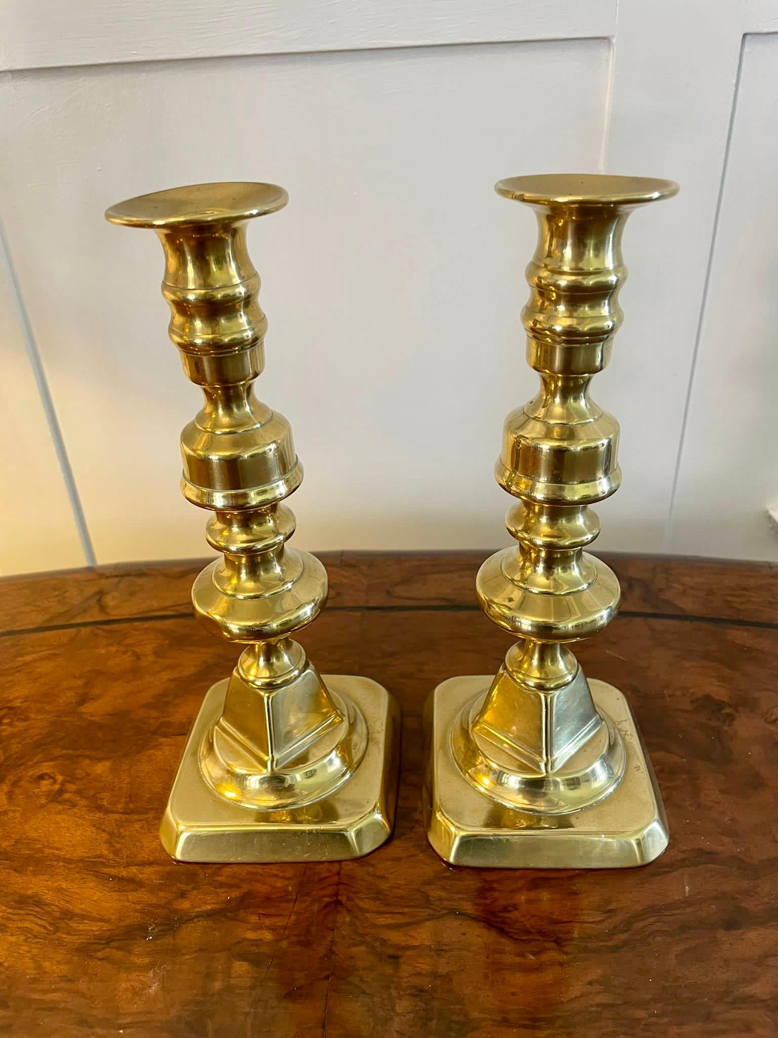 Pair of antique Victorian brass candlesticks having a shaped column raised on a square stepped base. 

Measures: H 22cm
W 9.5cm
D 9.5cm
Date 1860.
 