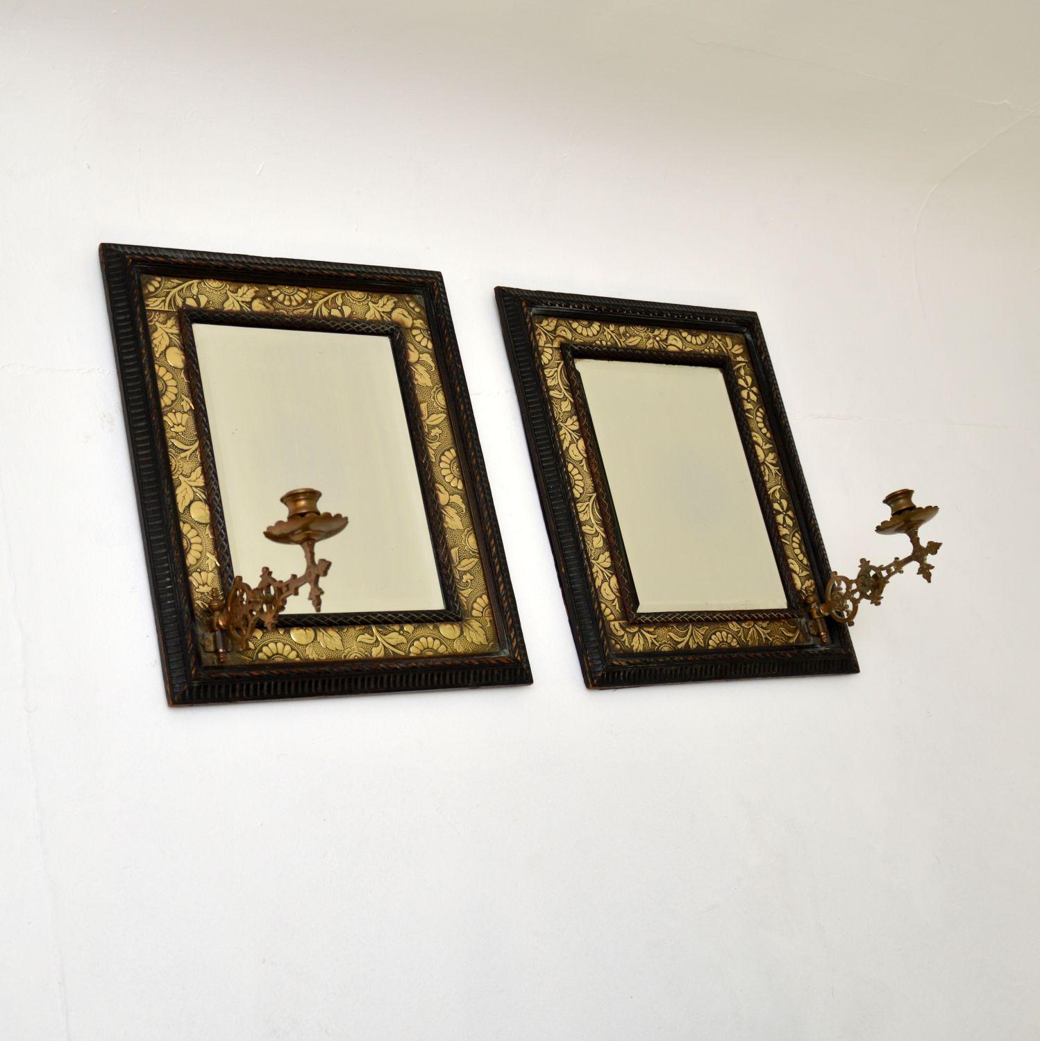 A superb pair of original antique Victorian bevelled mirrors in brass and carved ebonized wood frames. They were made in England, they date from the 1880s period.

They have quite an unusual design and are of amazing quality. Each has beautifully