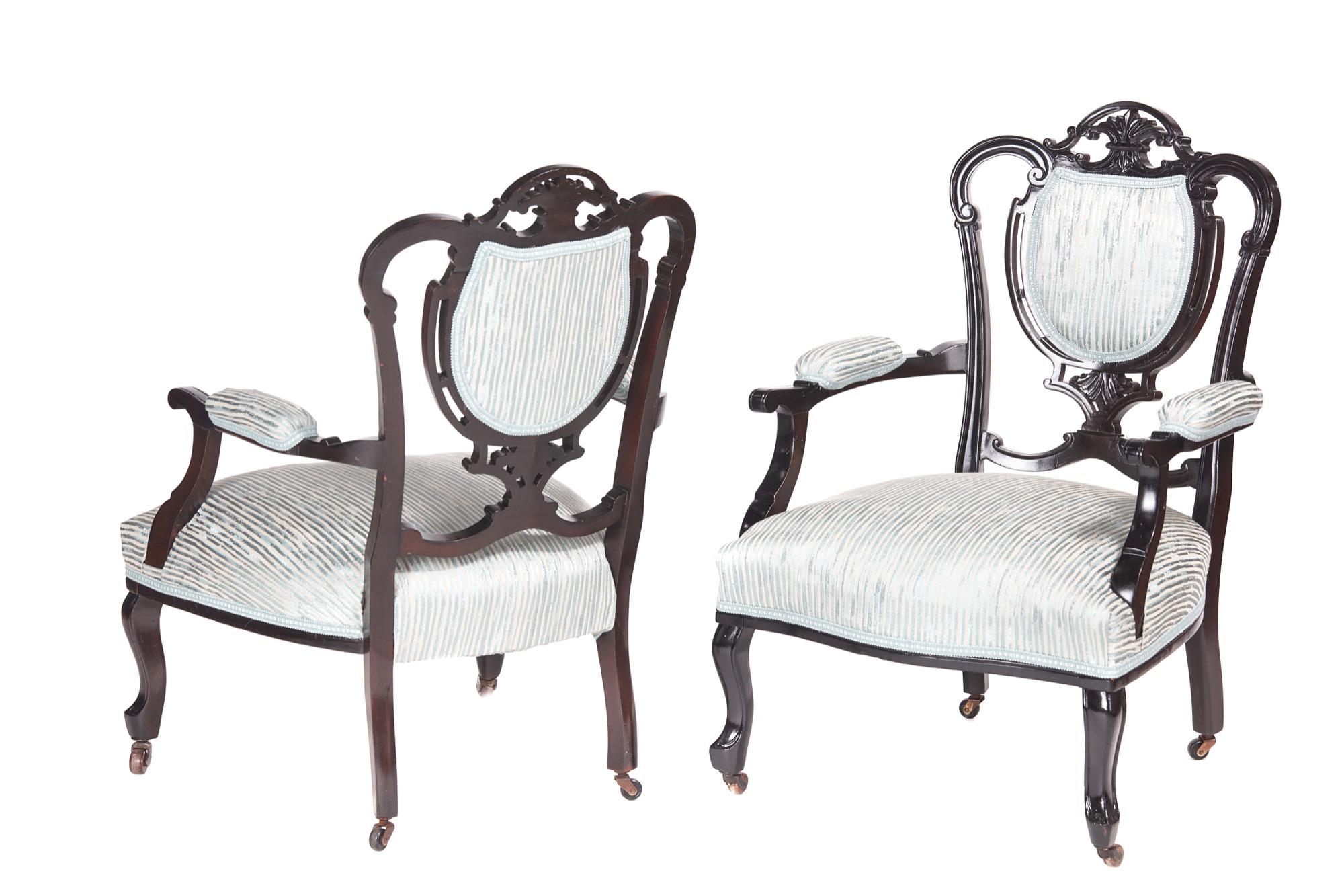 Pair of antique 19th century Victorian carved black lacquered library chairs, with lovely carved and shaped backs, shaped open arms, standing on cabriole legs to the front and out-swept legs to the rear. They have the original castors and have been