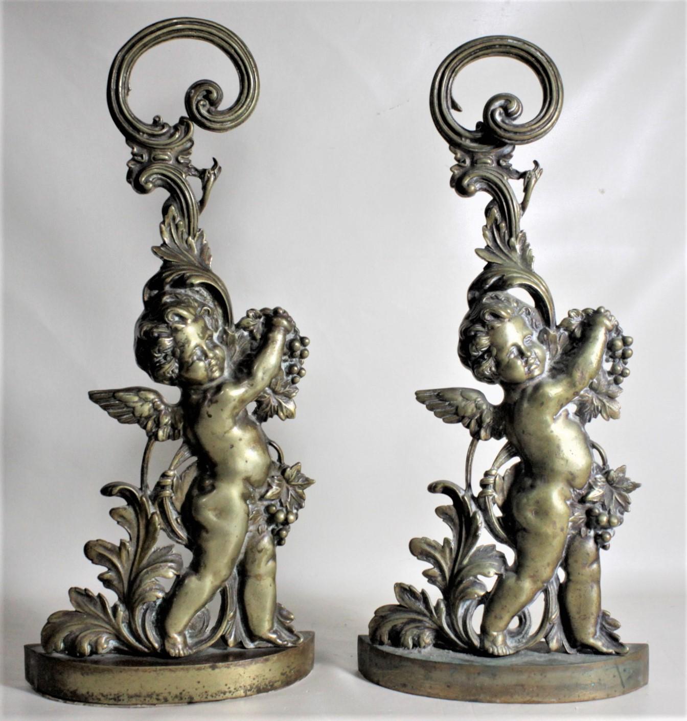 This pair of antique detailed cast brass figural cherub door stops are unsigned, but presumed to have been made in the United States in circa 1880 in the period Victorian style. These door stops each show a nicely executed cast brass figural cherub
