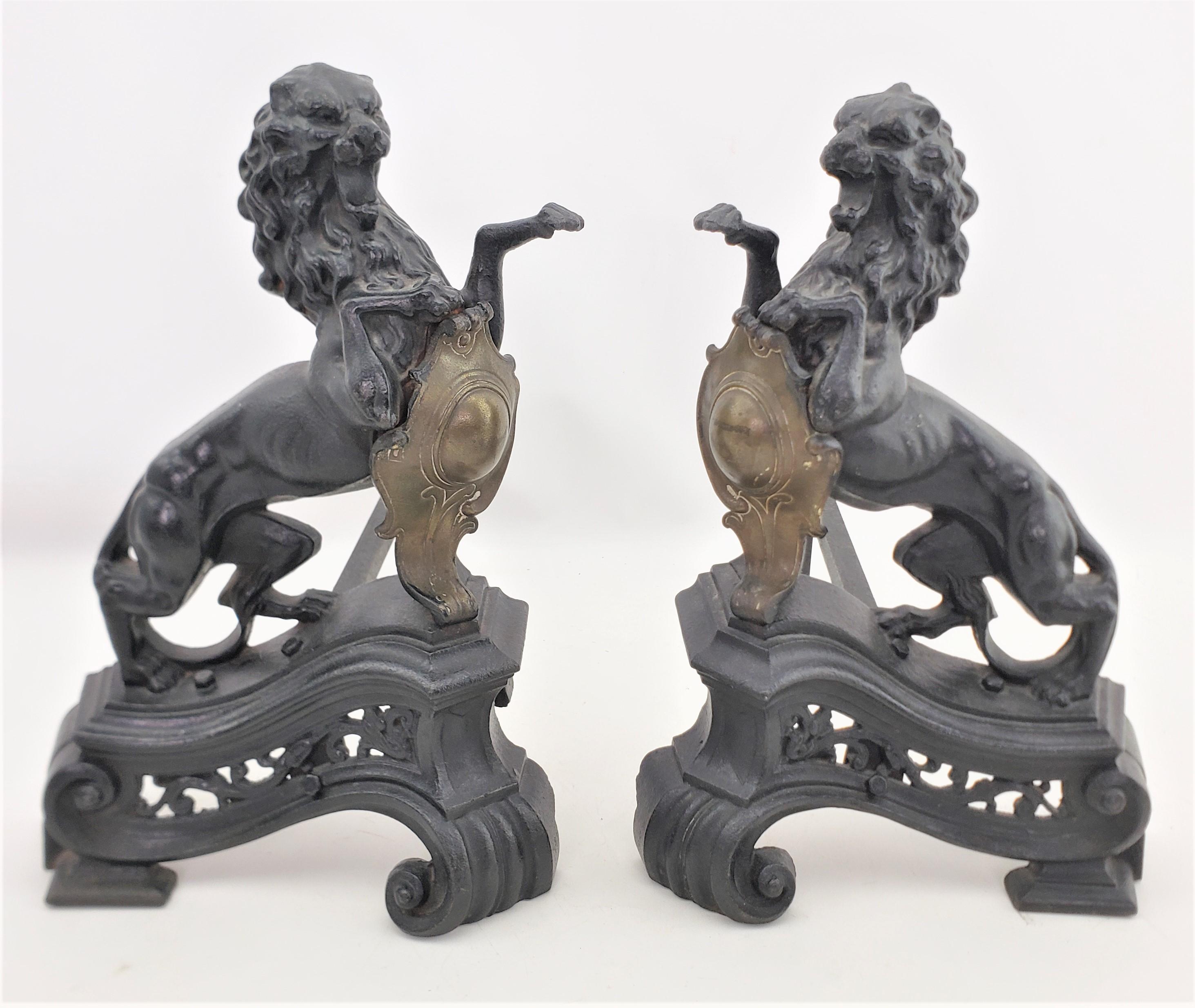 This pair of antique andirons are unsigned, but presumed to have originated from England and date to approximately 1880 and done in the period Victorian style. The andirons are done in ornately cast iron and depict rearing and roaring figural lions