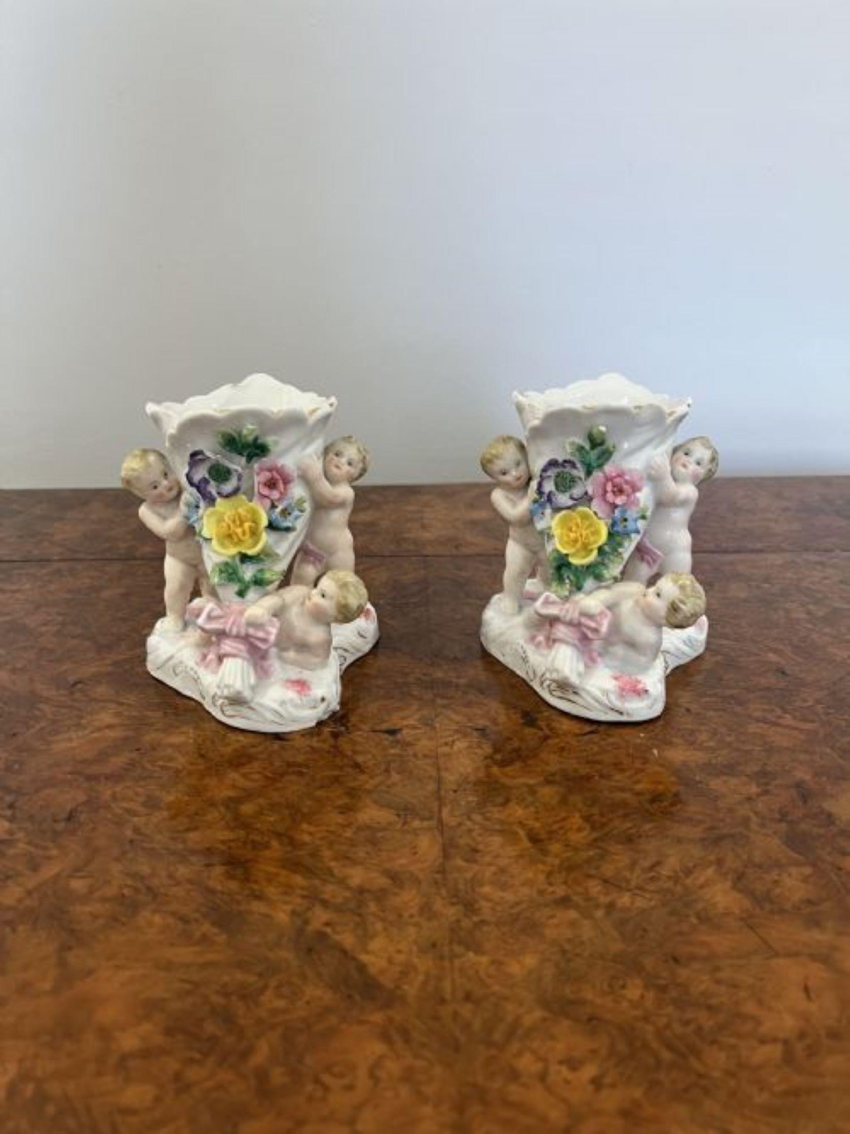 Pair of antique Victorian quality continental vases having a quality pair of antique continental vases decorated with three cherubs two standing at either side and one laying to the front surrounded by flowers in wonderful yellow, pink, blue, green,