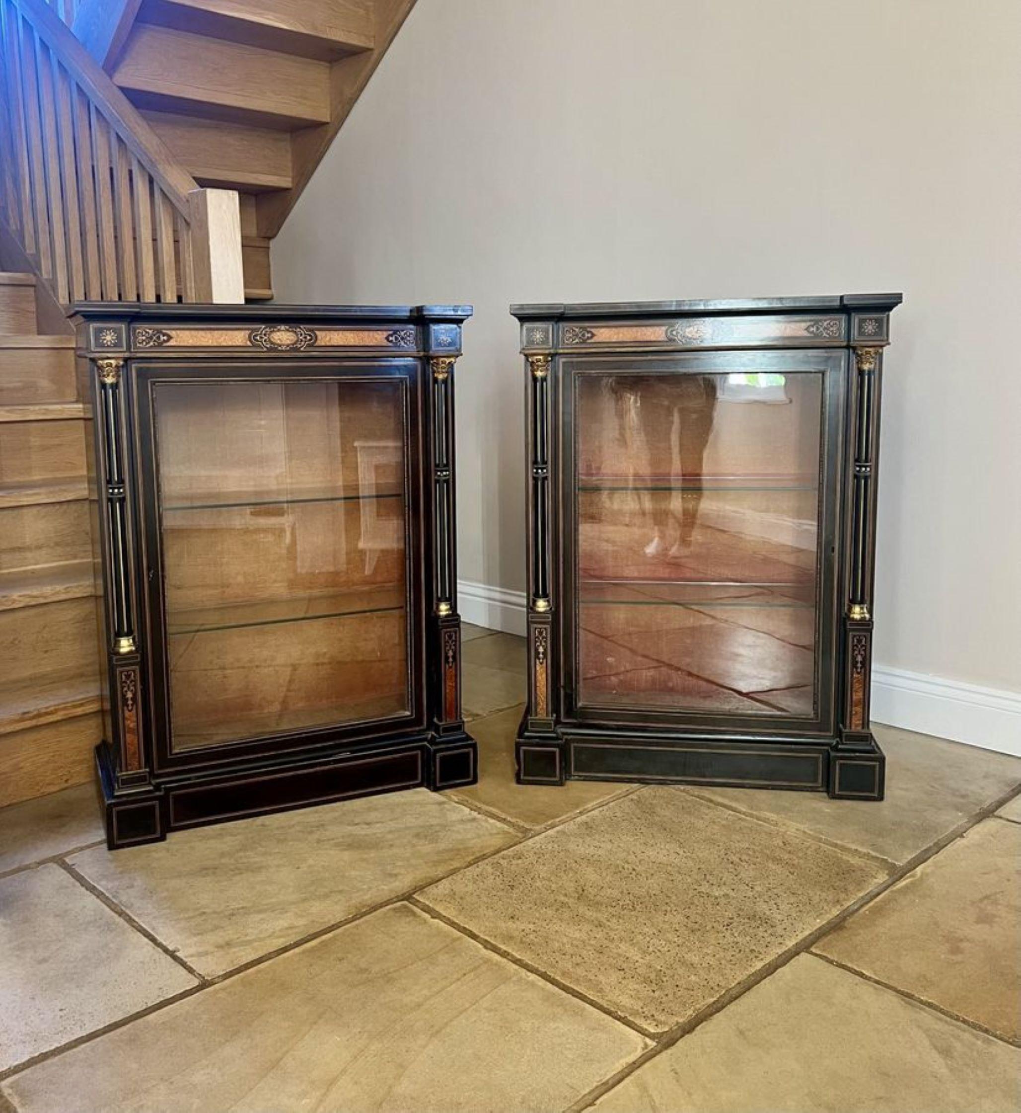 Pair of antique Victorian quality ebonised and amboyna inlaid side cabinets, having ebonised tops above an amboyna inlaid frieze single glazed door opening to reveal two glass display shelves, having reeded columns to the sides, standing on plinth
