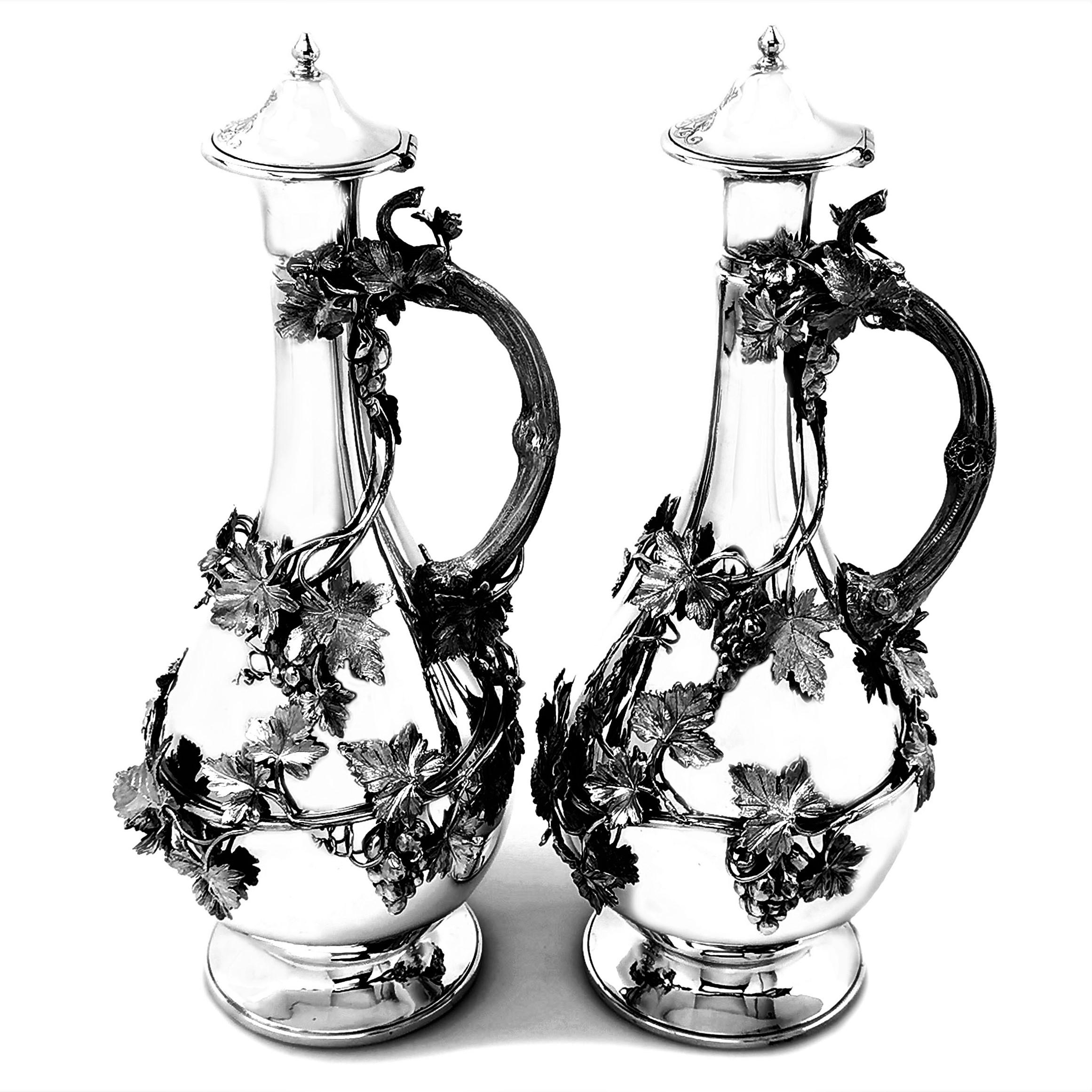 A magnificent pair of Antique Victorian Solid Silver Ewers with classic baluster shaped bodies and each standing on a spread pedestal foot. Each Jug is decorated with intricate applied vines with detailed leaves and grapes wrapping around the bodies