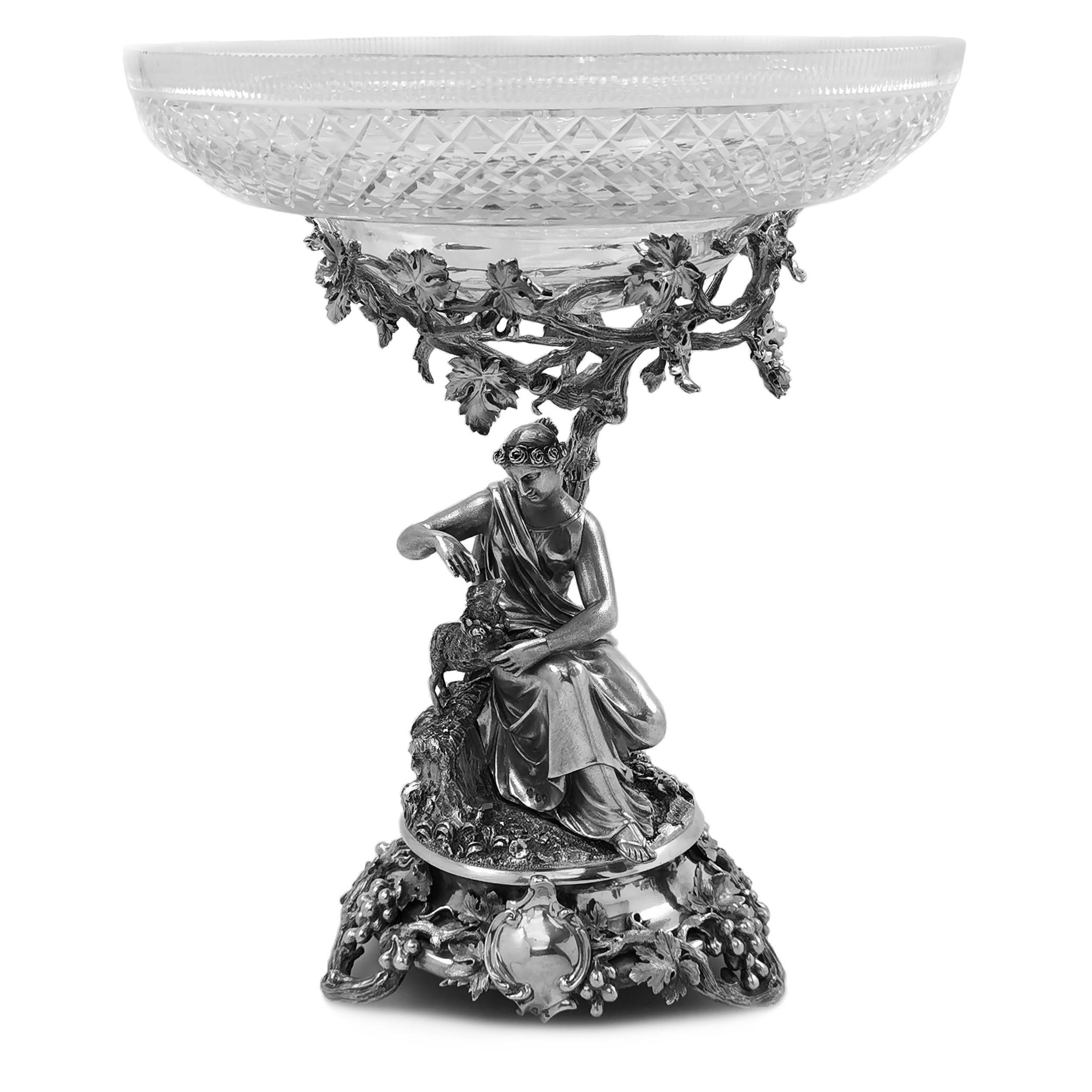 A pair of impressive antique Victorian silver comports with magnificent silver bases supporting elegant cut glass dishes. The silver bases each show a classical mythological style figure, one of a woman with a lamb beside her and the other showing a