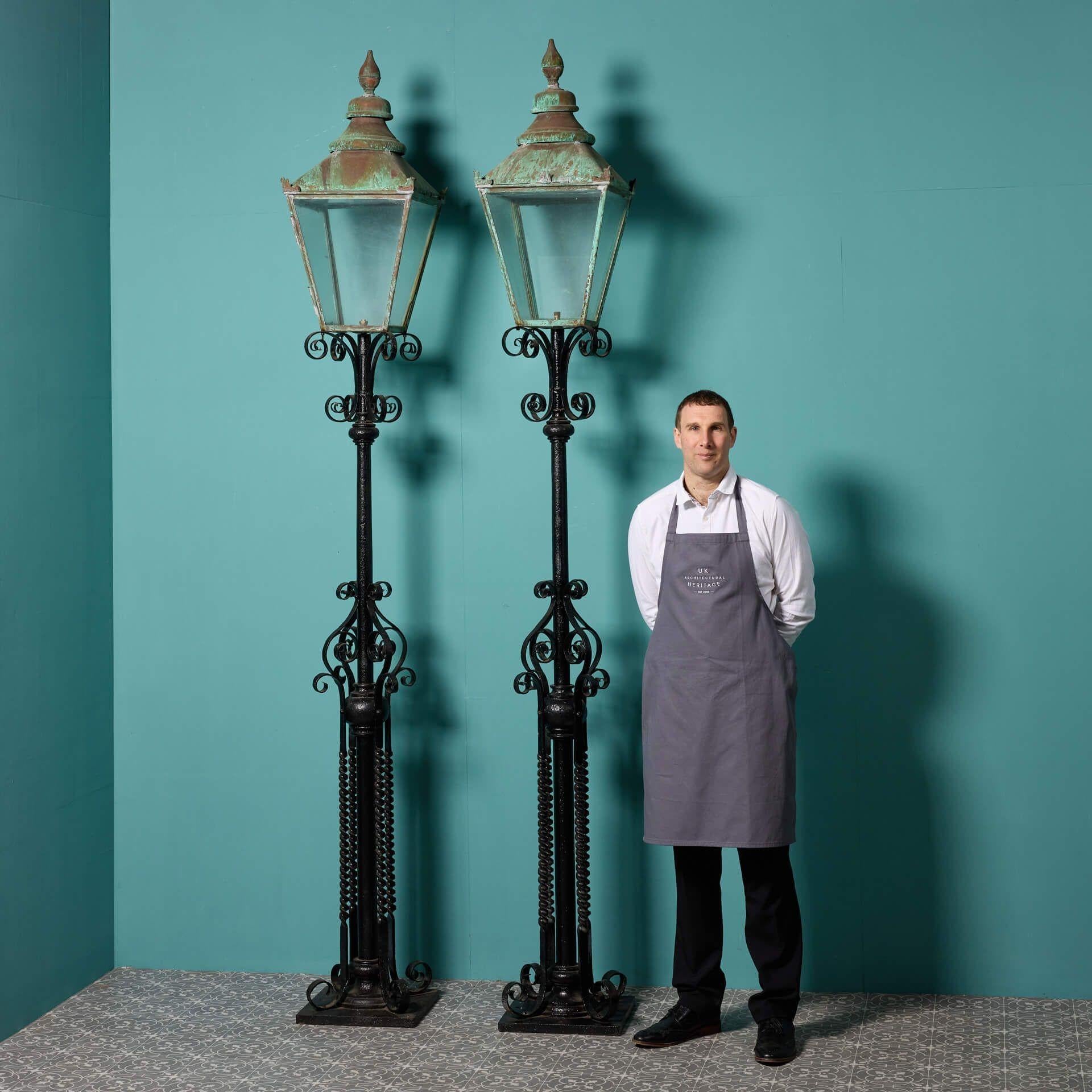 A pair of large antique Victorian lamp posts salvaged from a country house in Yorkshire. These decorative wrought and cast iron English lamp posts are beautifully styled with weathered copper tops, creating an unusual eye-catching verdigris