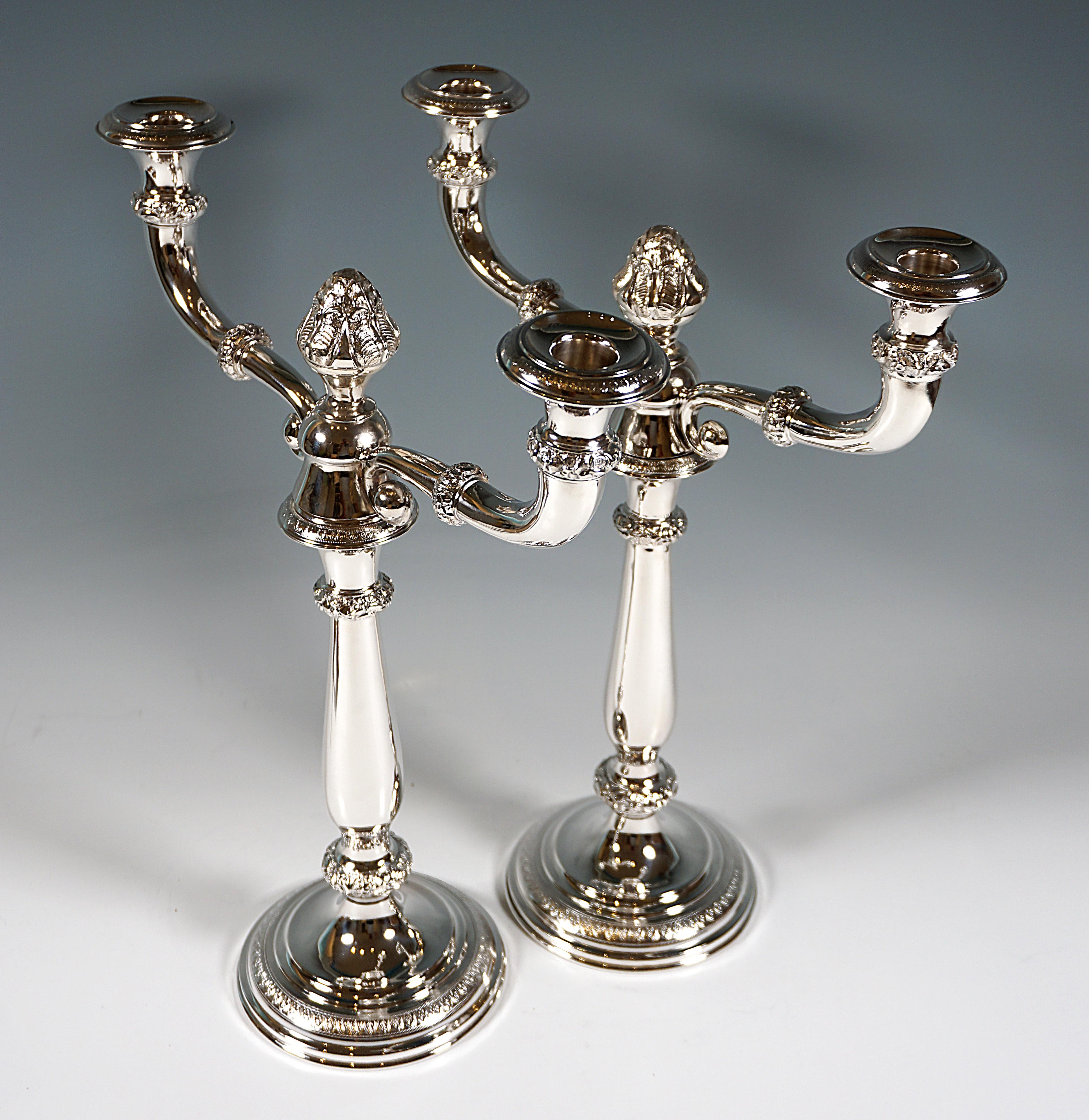 Two elegant silver candleholders on round stepped stand with palmette band, smooth baluster shaped stem, beaded rings decorated with sculpted floral & rocaille decor, vase shaped spouts with chased palmette decor on the high arched eaves pieces, can