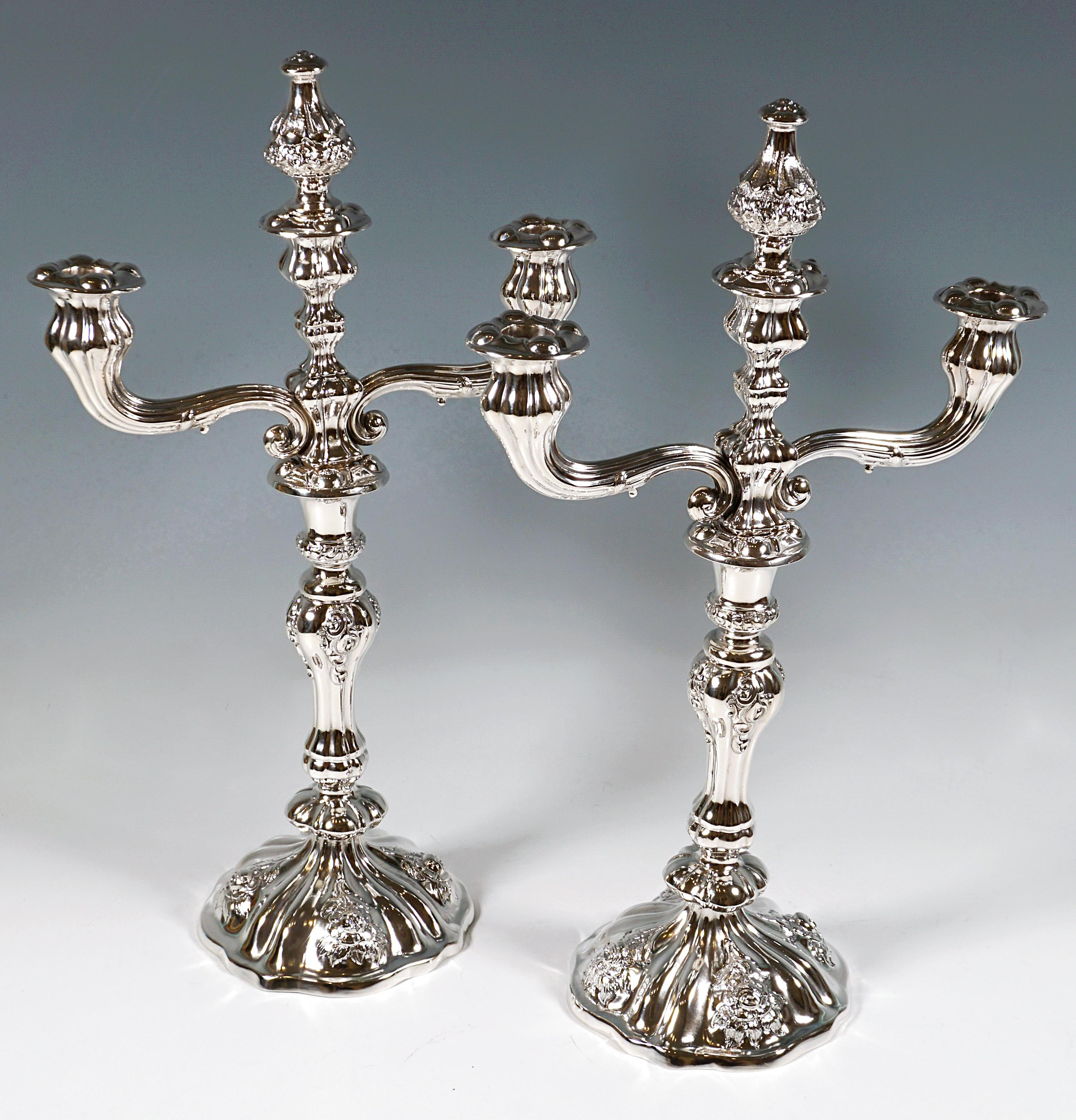 Dos candelabros festivos Biedermeier de plata sobre un soporte abombado de cuatro pasos con borde curvado, decoración de rosas cincelada y cincelada entre pliegues en relieve en el pie y el fuste en forma de balaustre, pico en forma de jarrón