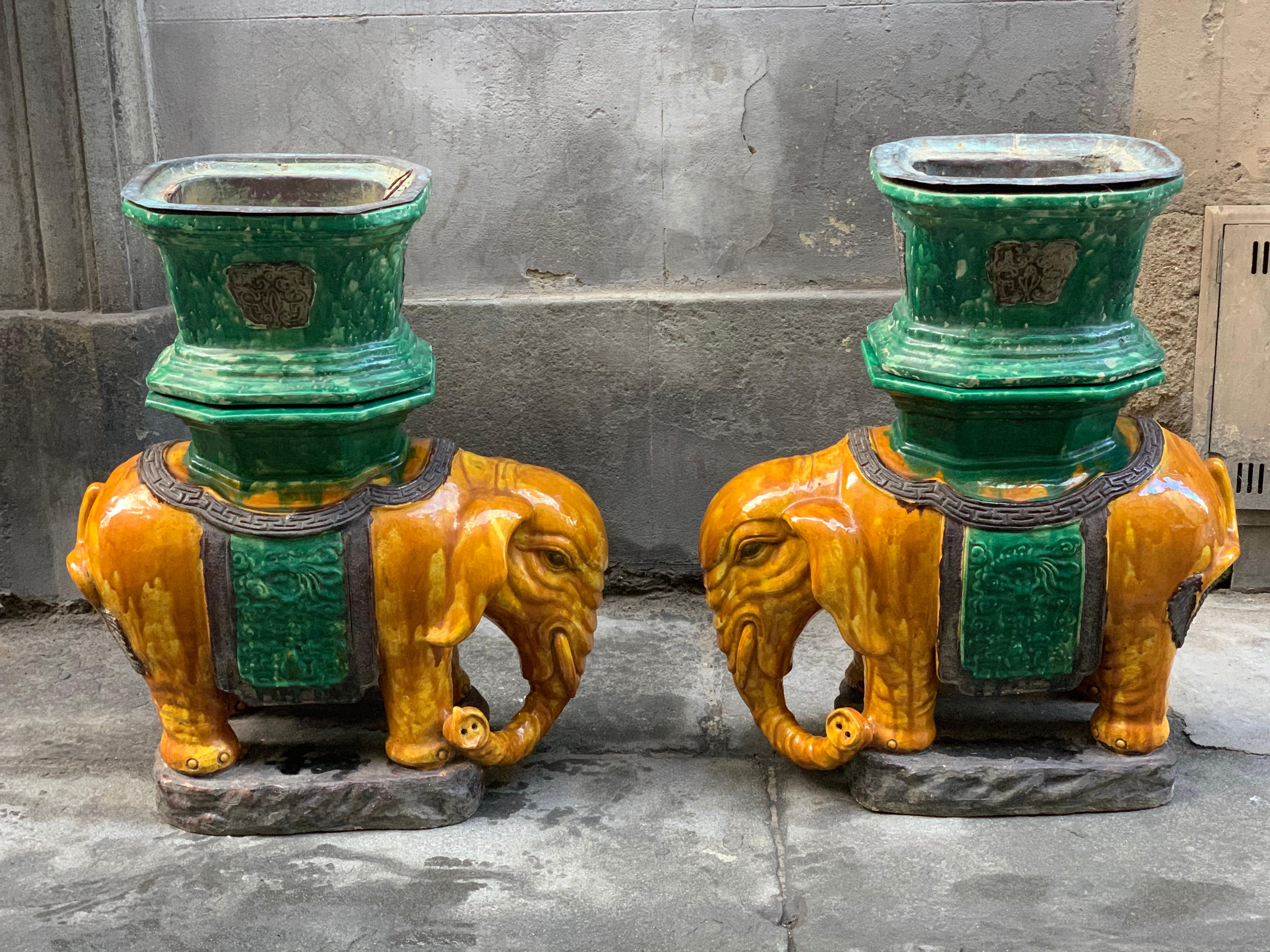 Pair of antique hand painted Vietnamese ceramic elephant stools/plant holder in a beautiful green and ochre yellow ceramic glaze. These charming elephants are made of two separate pieces, elephant statue and plant holder. They would work equally