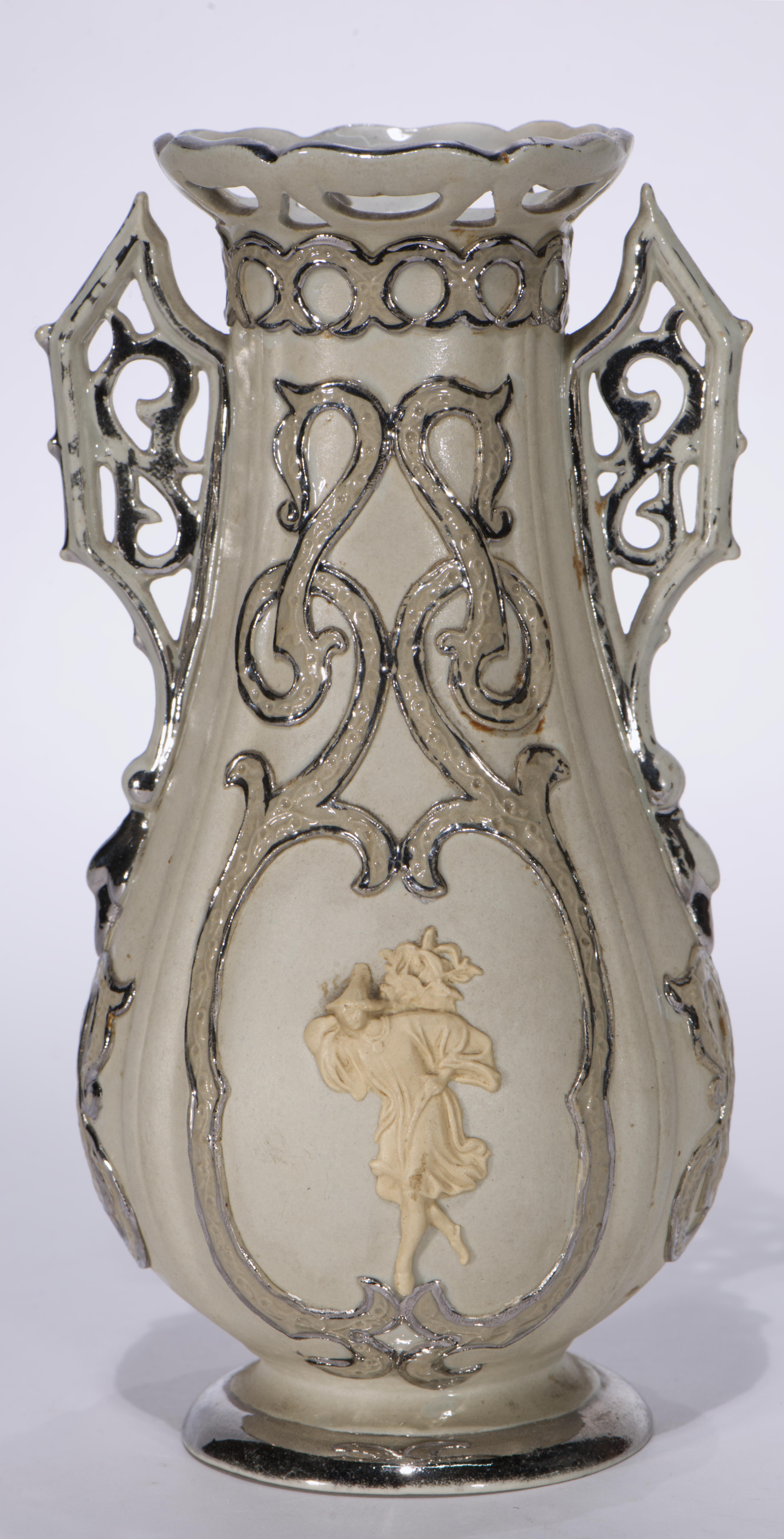  Pair of antique Villeroy & Boch early Mettlach Parian vases features elongated forms with flared reticulated rims, ornate reticulated twin handles, and Wedgewood style reliefs on the front and back sides of the vases. The reliefs depict a woman in