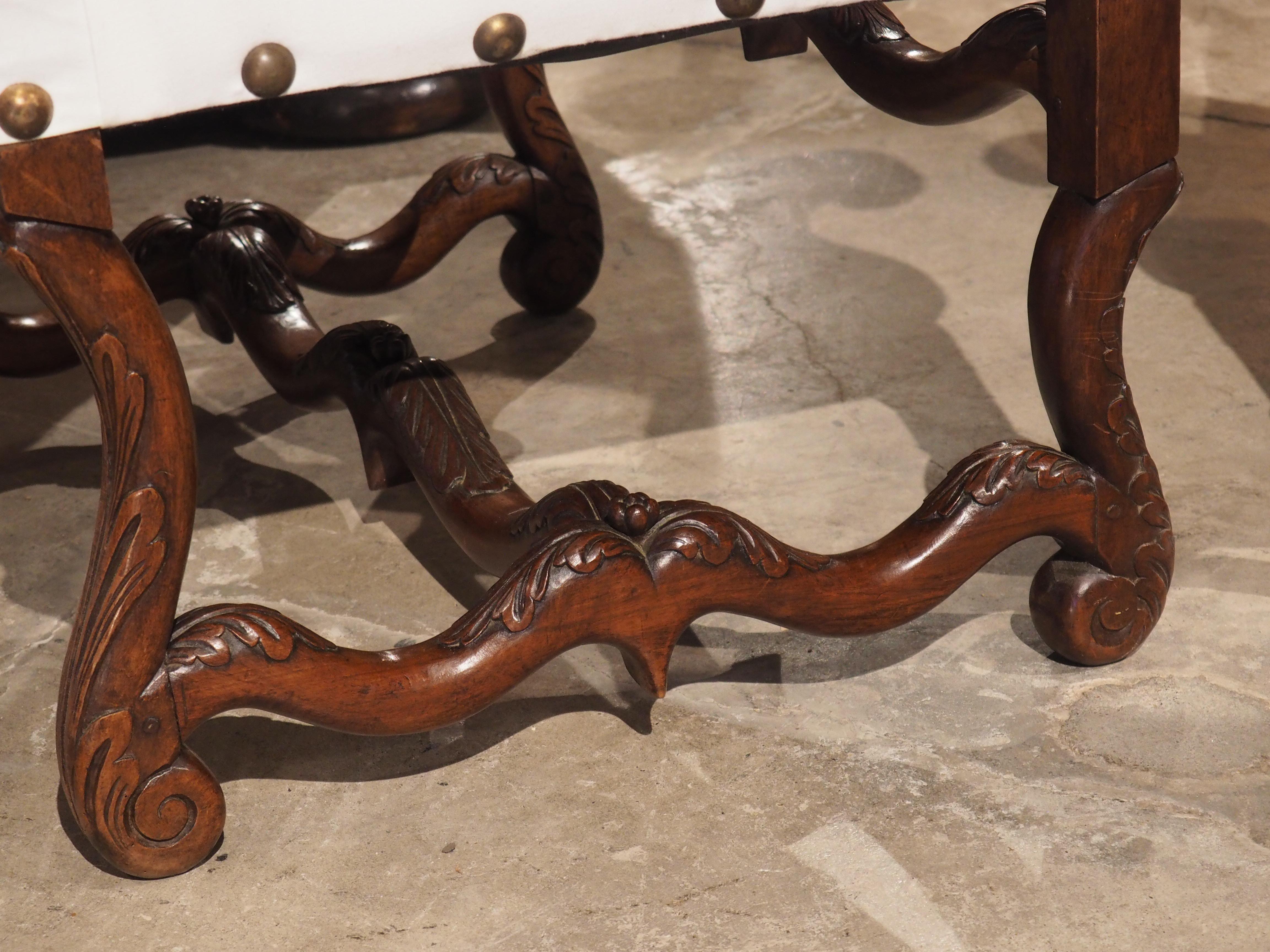 hand carved in walnut, circa 1830, this pair of antique armchairs were produced in the department of Lot, in southwestern France. Sinuous arms extend from the front of the large, slightly reclining back rest. Each arm is adorned with two carved