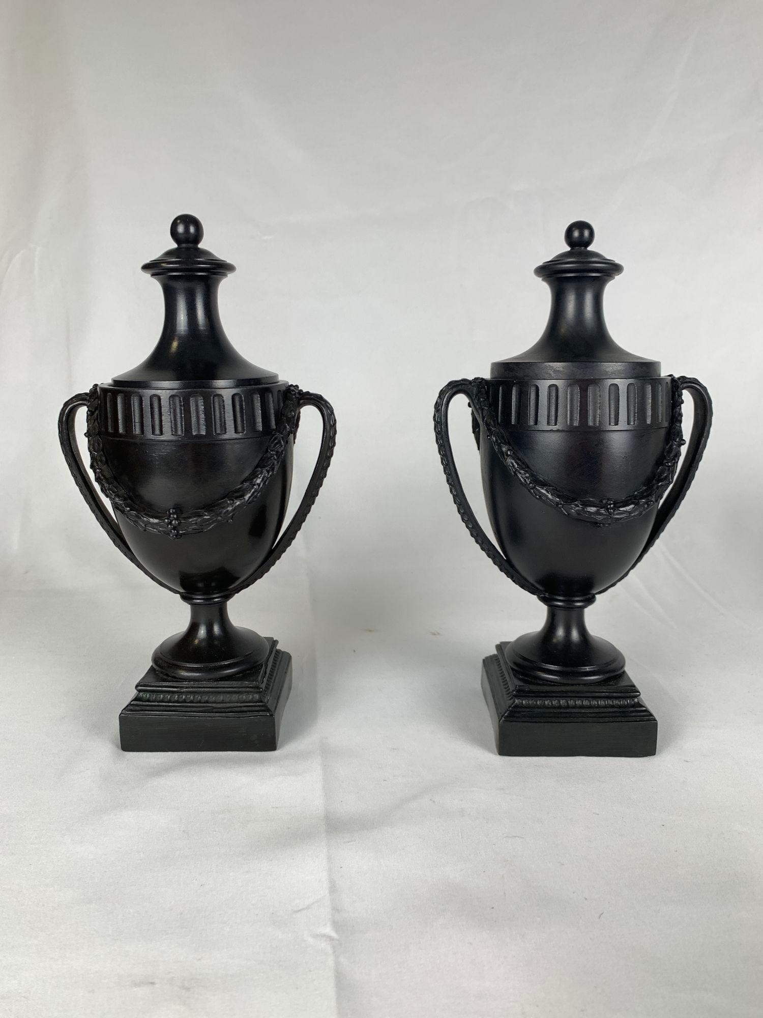 Questa coppia di urne in basalto nero di Wedgwood & Bentley, realizzate nella rinomata fabbrica Etruria intorno al 1775, esemplifica la raffinata semplicità del design neoclassico.
I corpi ovoidali, lisci e affusolati, poggiano su basi quadrate,