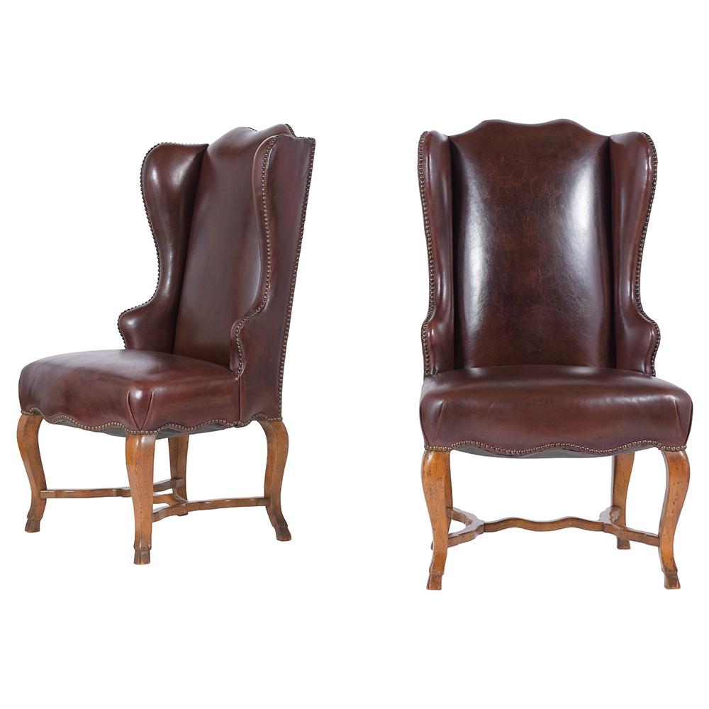 A fabulous pair of French provincial wingback chairs beautifully crafted out of walnut wood and features its original distressed leather in good condition newly dyed in dark brown color with a brass nailhead trim decor. These lounge chairs are very