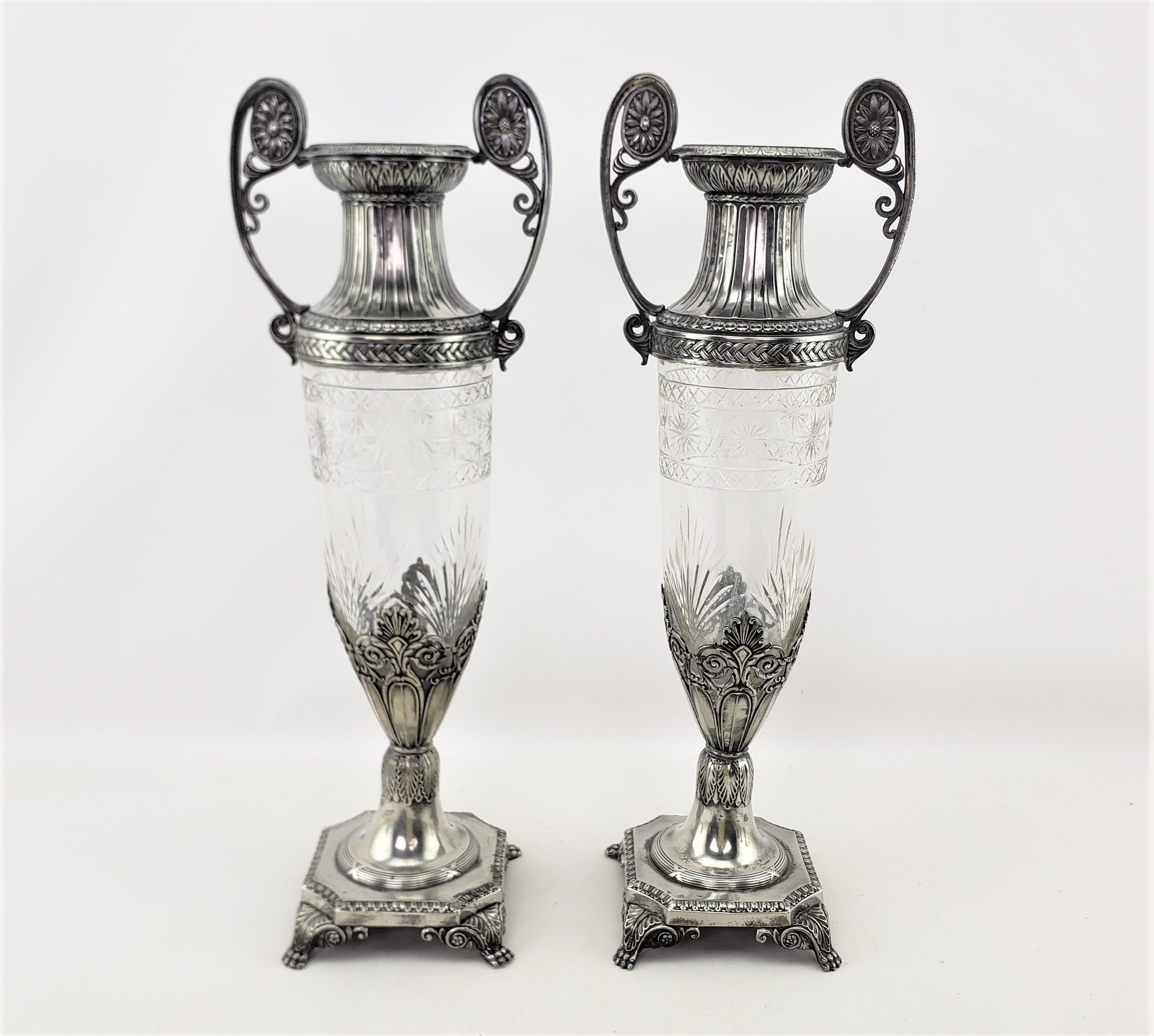 Cette paire de vases anciens a été fabriquée par la célèbre société WMF d'Allemagne vers 1900, dans un style sécessionniste. Les vases sont constitués d'un corps en cristal taillé et effilé, avec des montures argentées ornementées sur le dessus, les