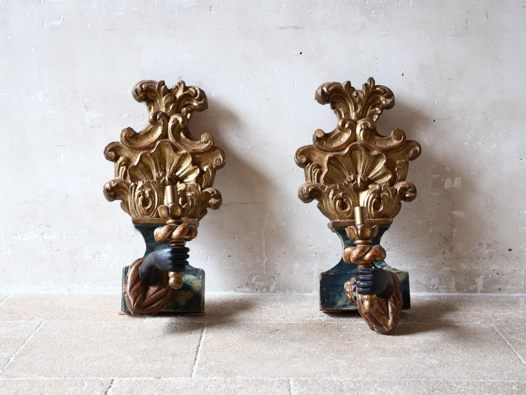 Pair of antique Venetian wood-carved Blackamoor arm-and-hand wall sconces with blue patina and gilt details.

Wired and fitted wih E14 fittings.

h 66 x w 34 x d 40 cm