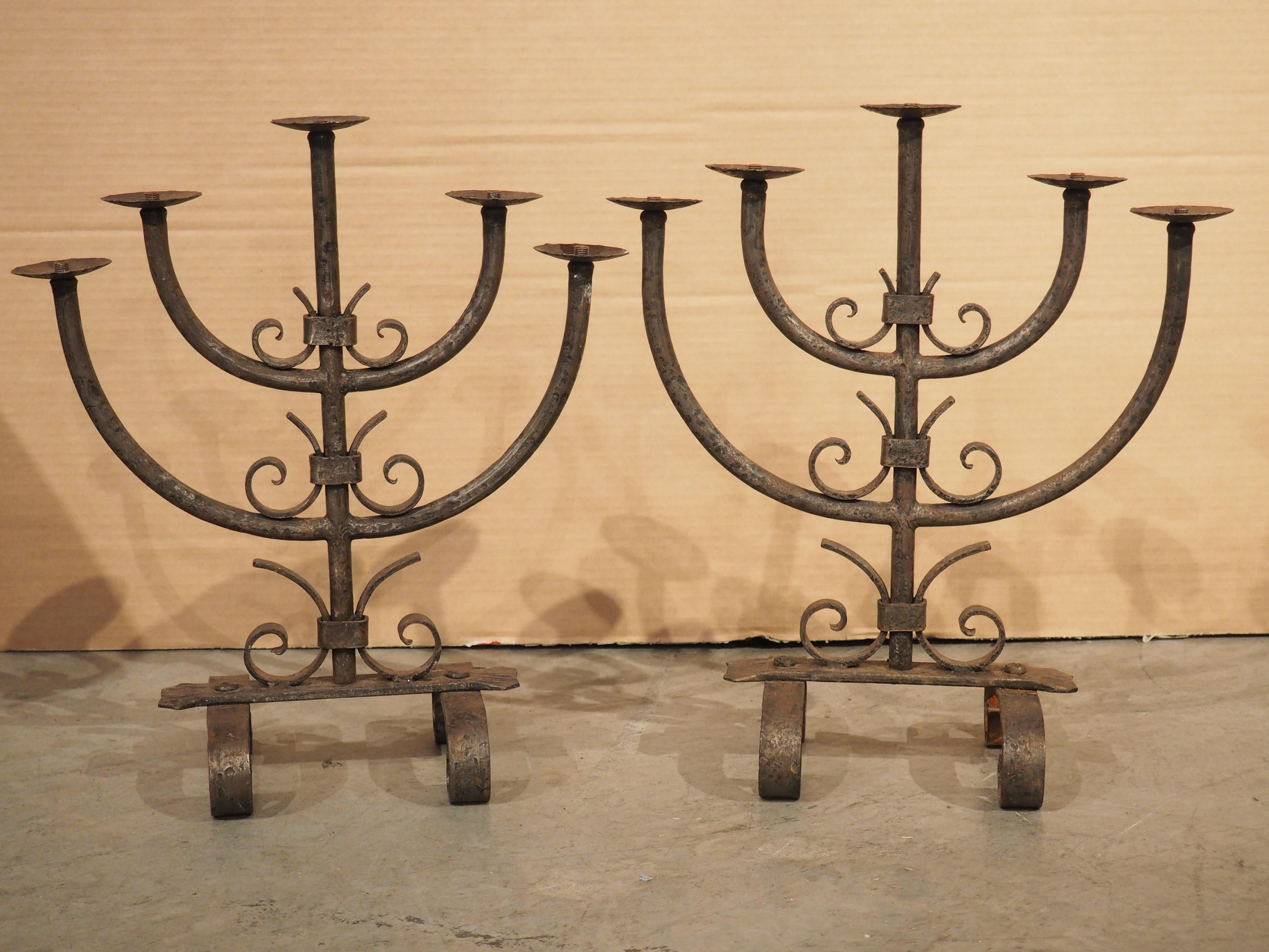 Wrought iron is tough, yet malleable, allowing the metal to be worked into elaborate scrolls and other sinuous motifs. This pair of wrought iron candelabras from Bordeaux, France (circa 1900), features two demi-lune arms and several bracketed