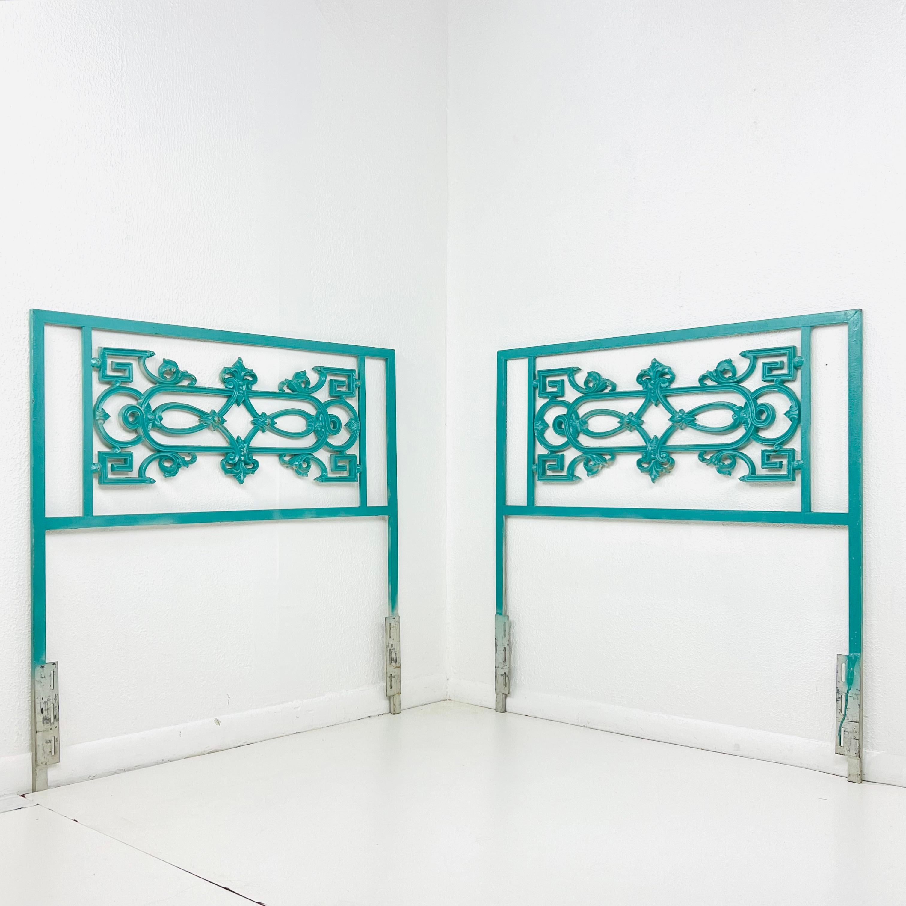 Pair of chic twin size wrought iron headboards with Greek key and fleur de lis design. Bolts to standard metal bedframe. Overall good condition with some wear to painted finish from age and use. Previously repainted in teal (or ask us for a