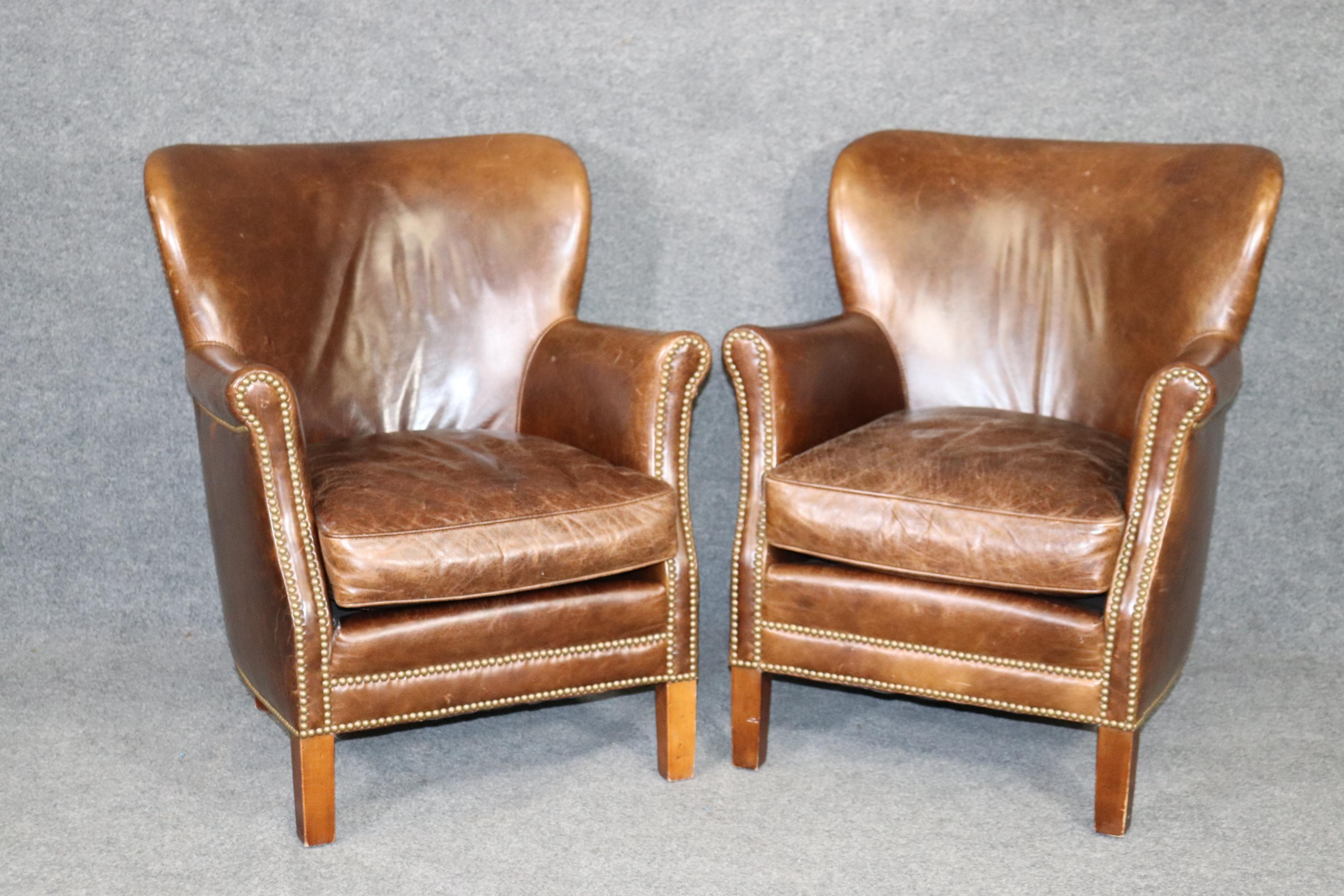 This is a fantastic pair of Antique -looking aged leather club chairs by Lee Industries leather of North Carolina. They made these chairs to look antique with intentionally distressed leather and look fantastic and well-lived in. The chairs have