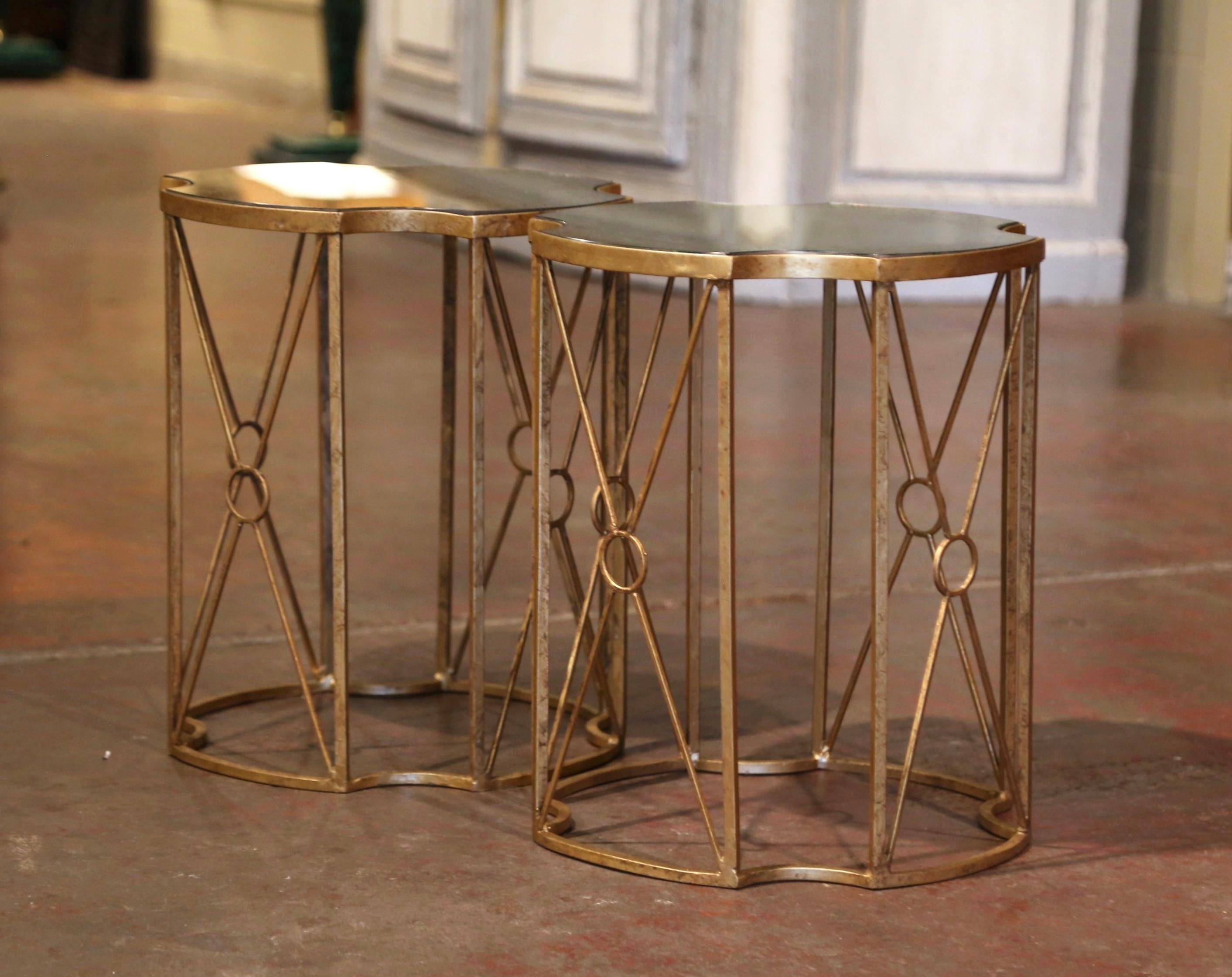 Decorate a living room or a den with this elegant pair of occasional tables. Each table has straight legs with X decor in between, and attached at the base with a decorative frame stretcher. The top is dressed with an inset smoked mirrored glass.
