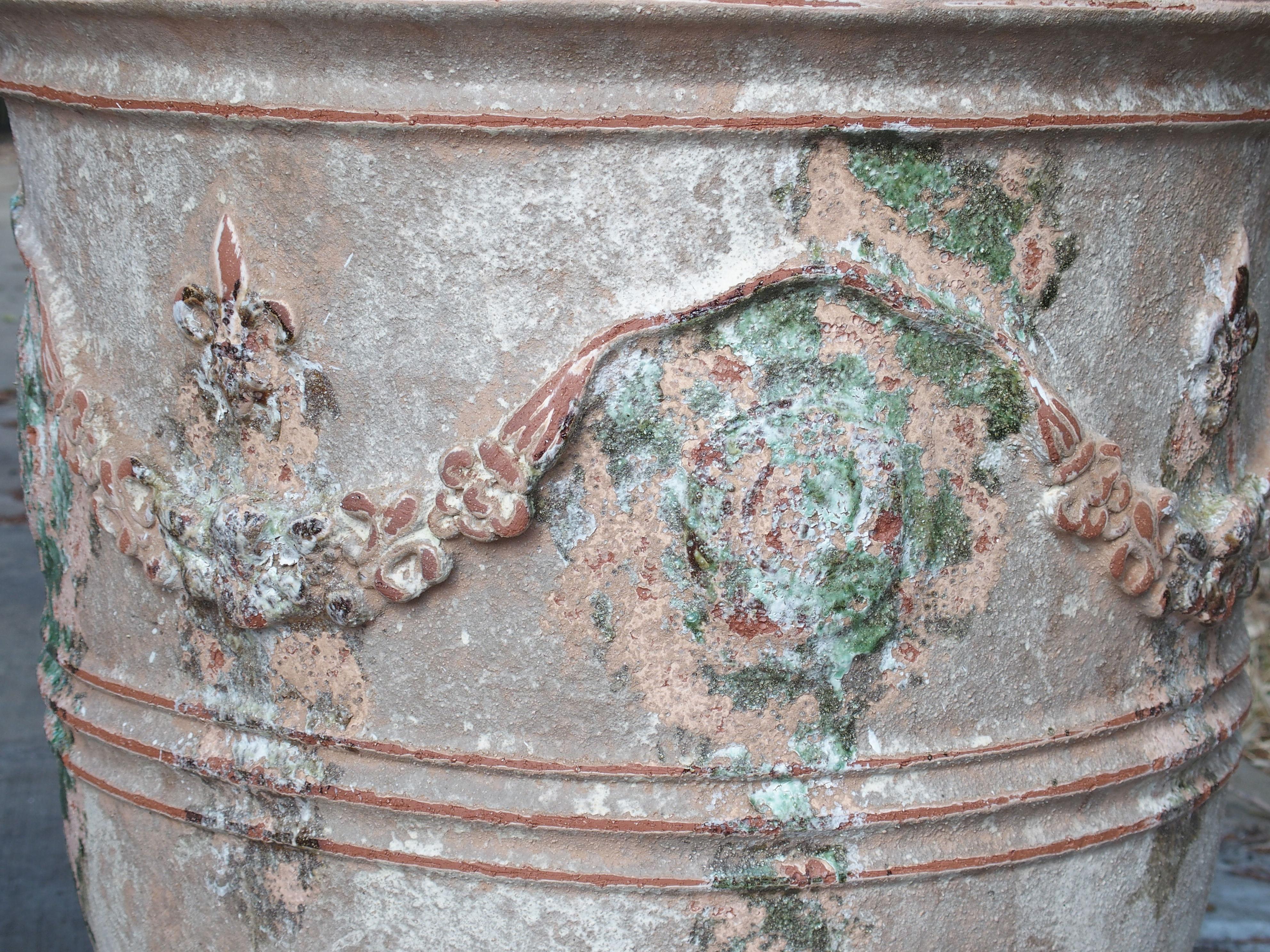 These large Anduze pots have been beautiful finished with a powdery matte white over terracotta and purposely distressed. They are adorned with garlands and fleur-de-lys, and have splashes of glazed-over green paint near the Anduze markings.