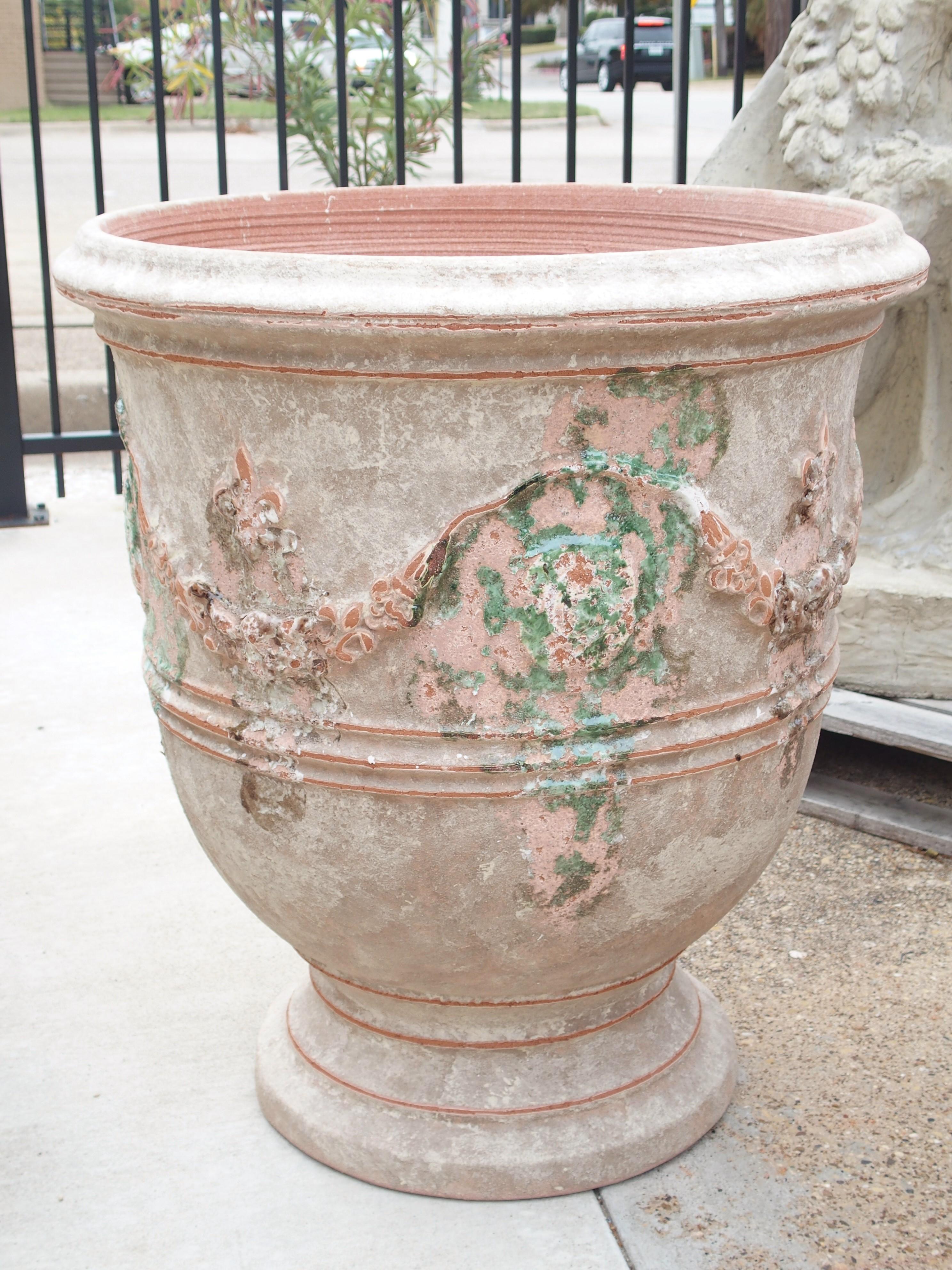 These large Anduze pots have been beautifully finished with a touch of matte white over terracotta and purposely distressed. They are adorned with garlands and fleur-de-lis, and have splashes of glazed-over green paint near the Anduze markings.