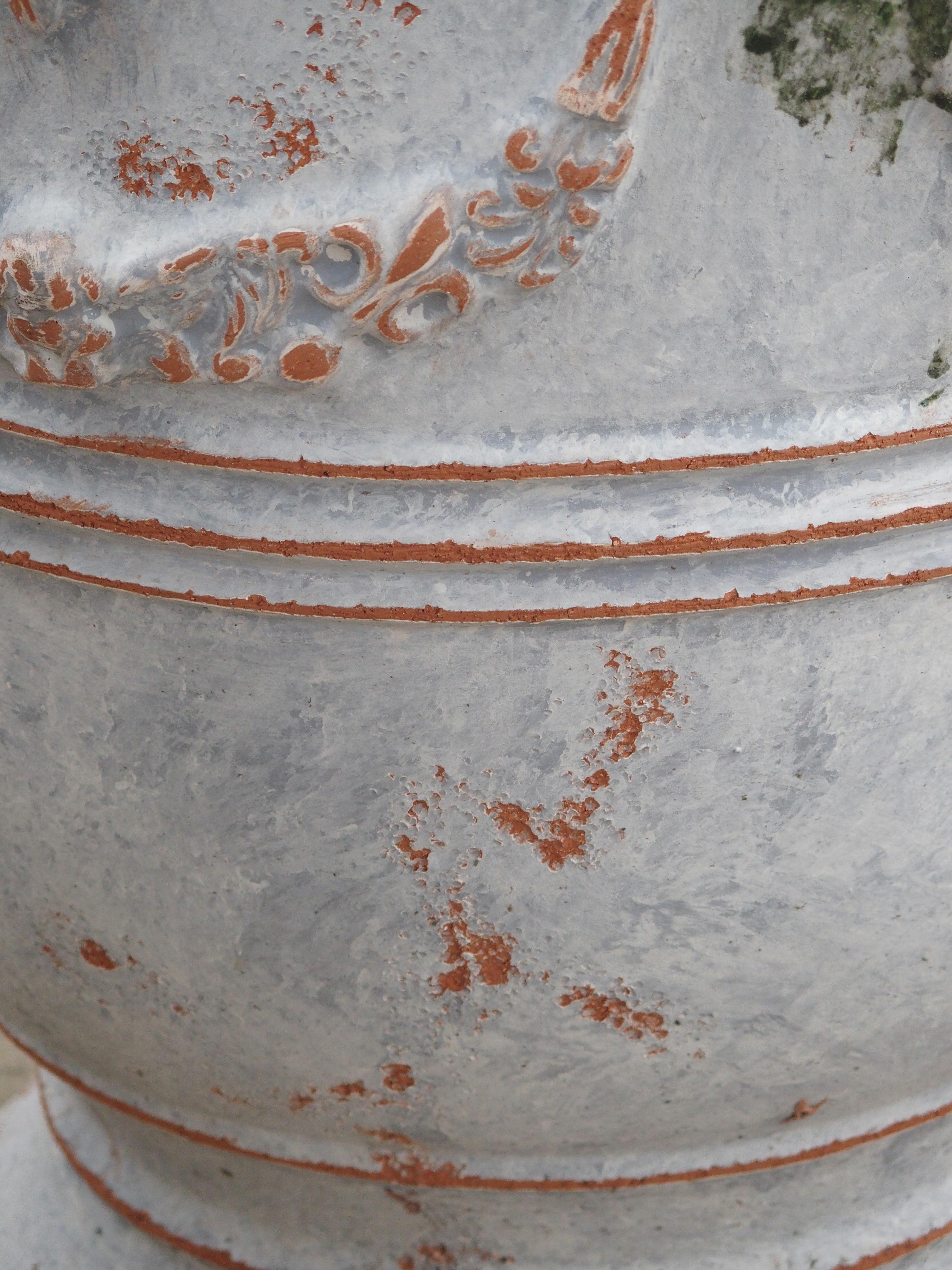 These wonderfully painted Anduze pots have been finished with a matte white and blue-grey paint and purposely distressed. They are adorned with garlands and fleur-de-lis, and have splashes of glazed-over green paint near the Anduze