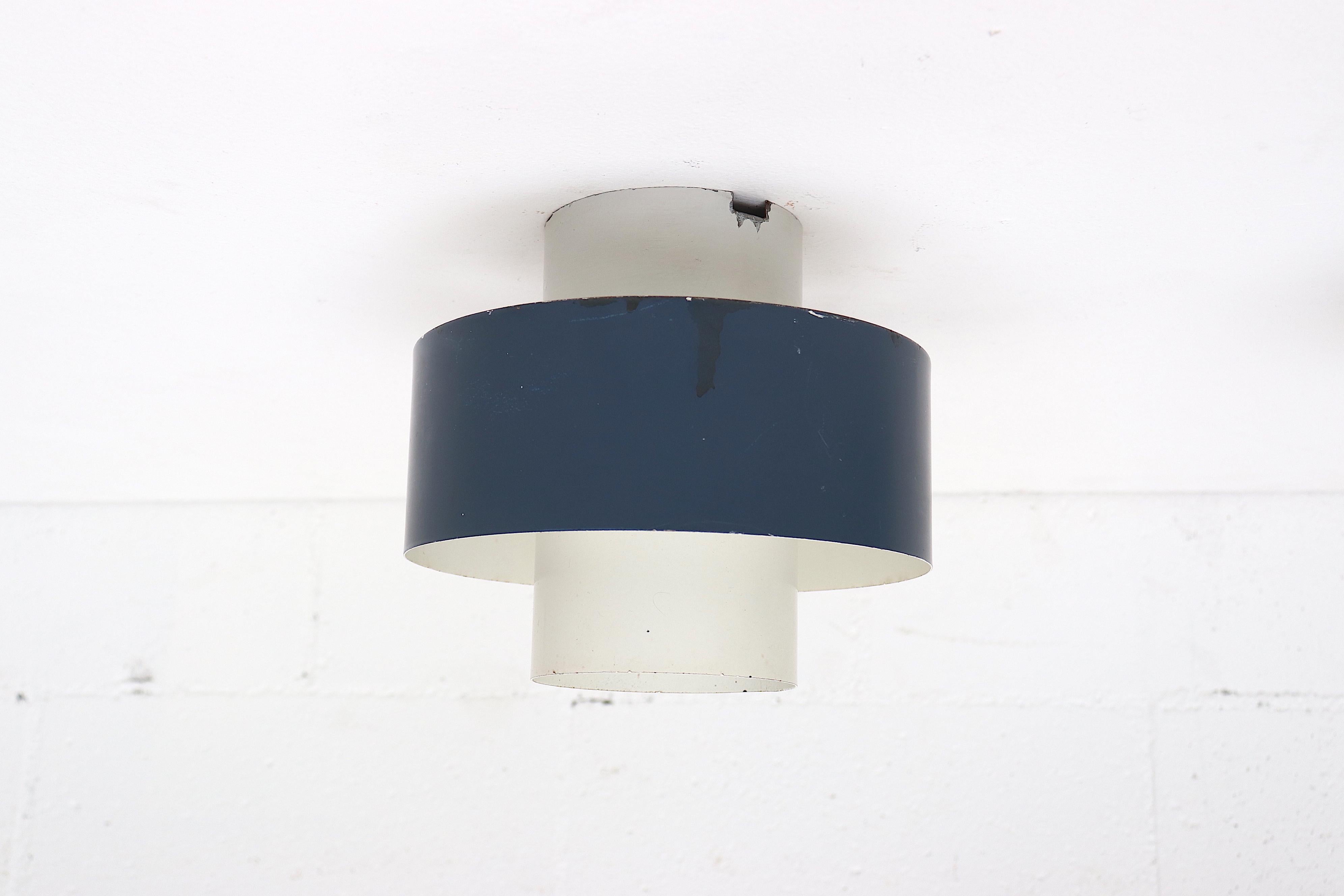 Pair of Anvia midcentury navy and white flushmount ceiling lamps. In original condition with some enamel wear, visible scratching and staining. One has a cut-out at the base of the flush mount neck, does not deter from the lamp or structure. Set