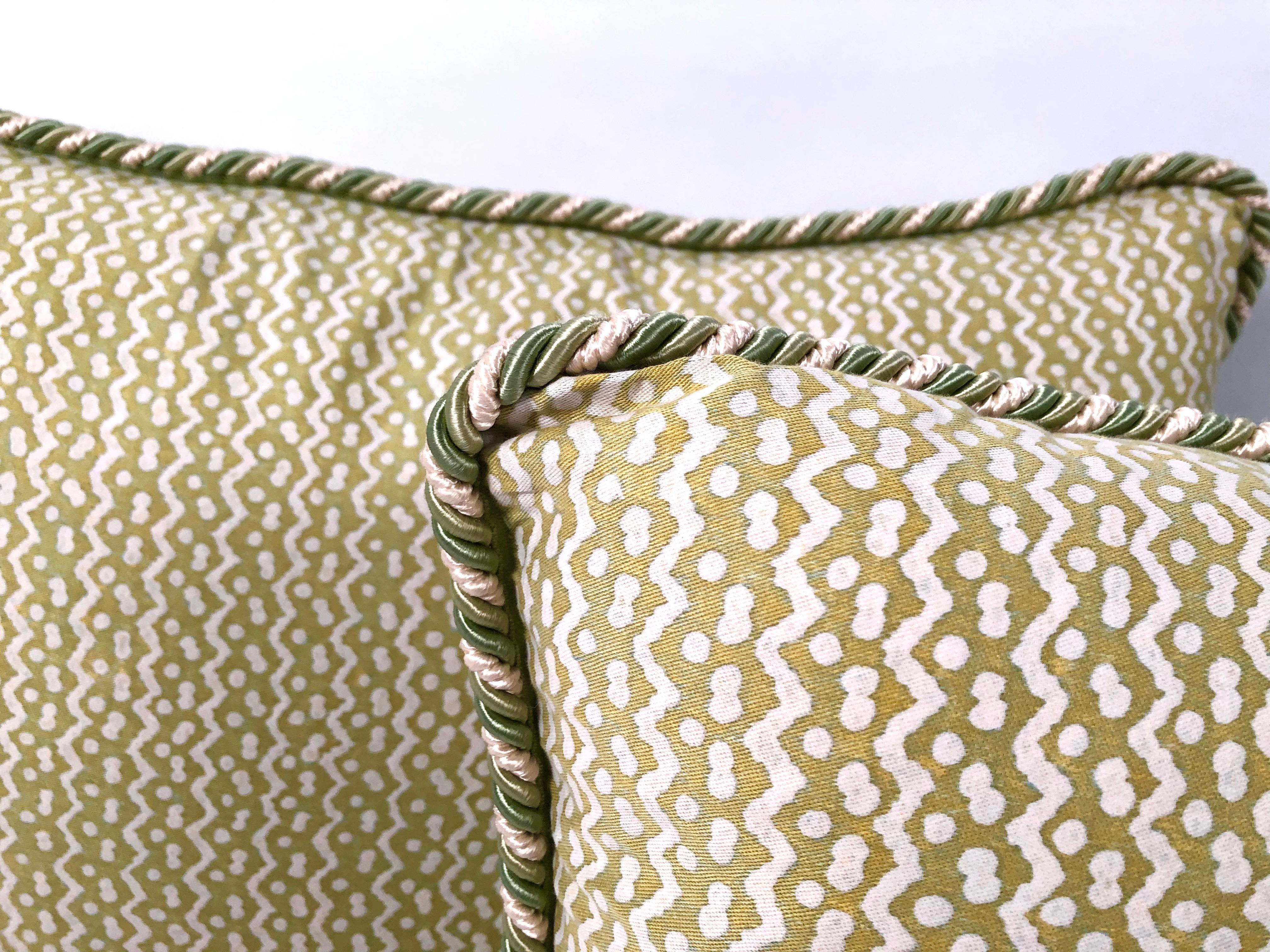 A pair of original Fortuny fabric Tapa pattern pillows in white on apple green, featuring zig zag lines and dots characteristic of Fortuny's distinctive hand made and proprietary technique, down filled and backed with high quality wool velvet with