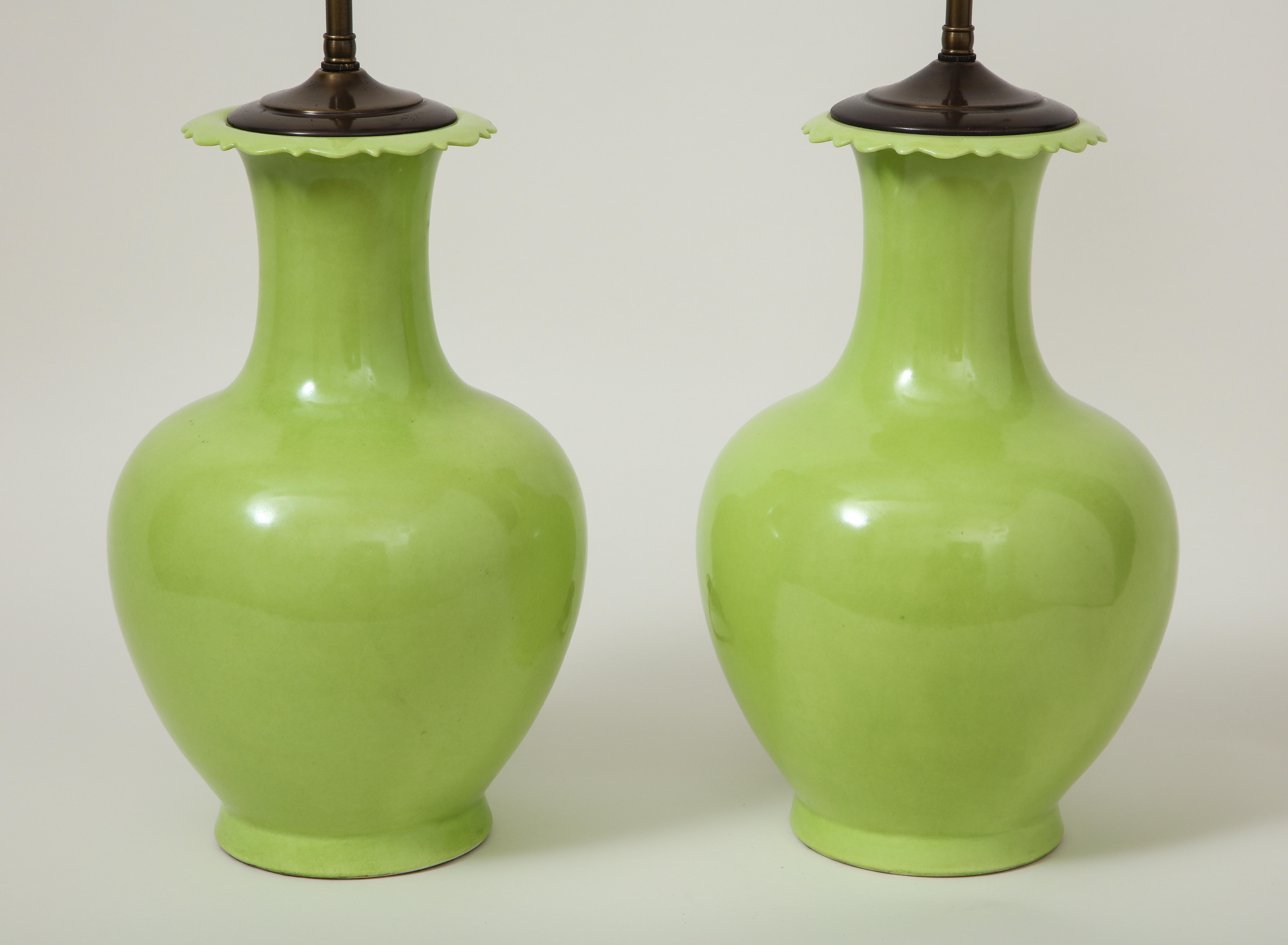 Each of baluster form with scalloped rim, fitted with an adjustable rod and two-light sockets. Height to top of vase is 14.75