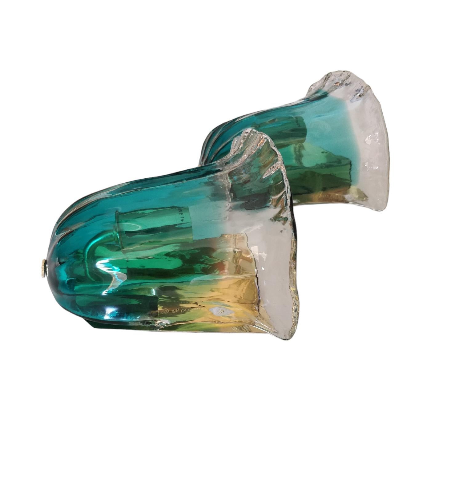 The design of these wall sconces is elegance and refinement, with the glass shaped like a flower that delicately blends green and transparent glass elements to create a captivating visual effect when the light shines through. The glass with a green