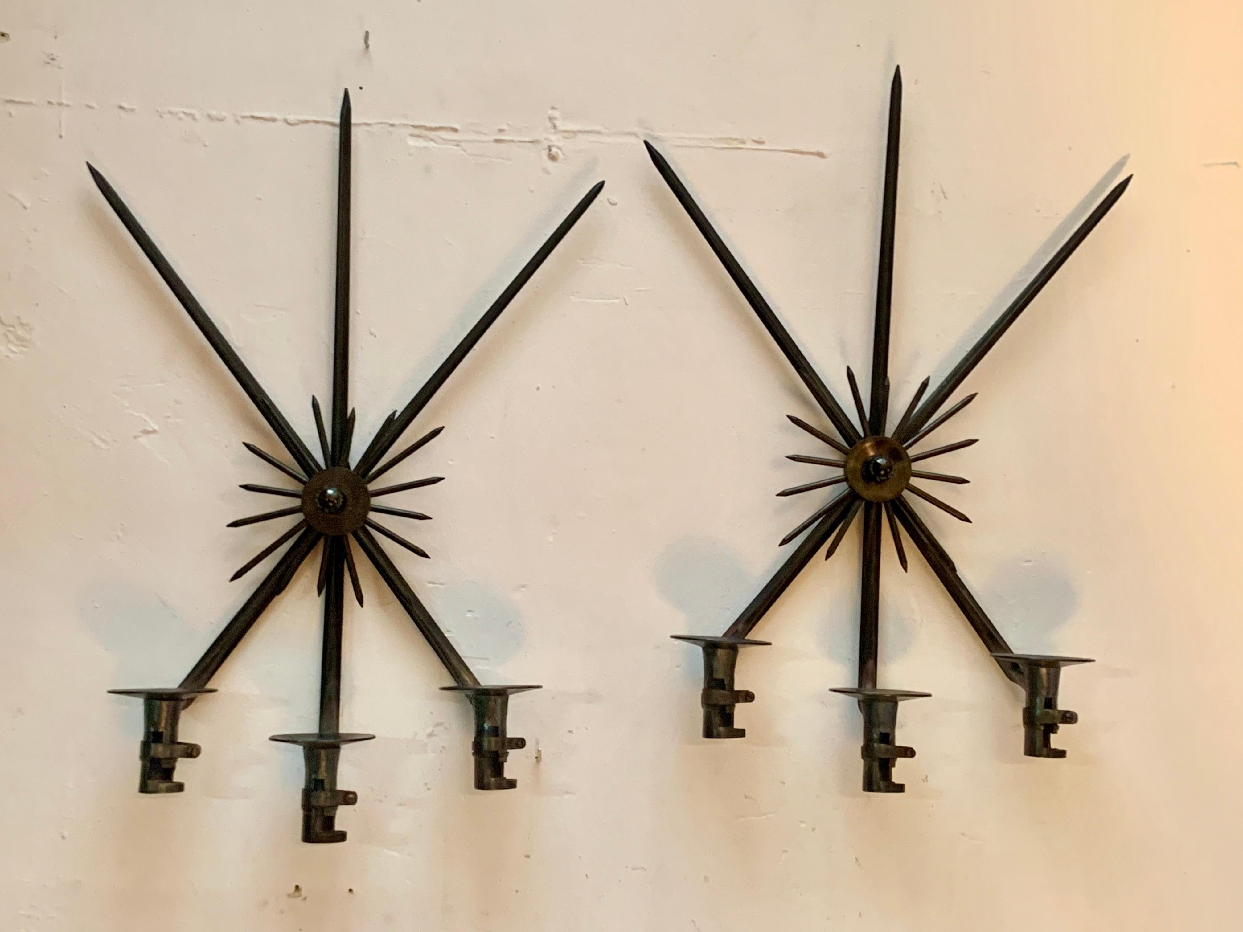 Ein Paar origineller Wandleuchter mit einer natürlichen Kerze, hergestellt aus alten Bajonett-Waffen, in Form eines Kreuzes mit drei Sockeln für die Kerzen und einem zentralen Ornament in Form von Sonnenstrahlen.