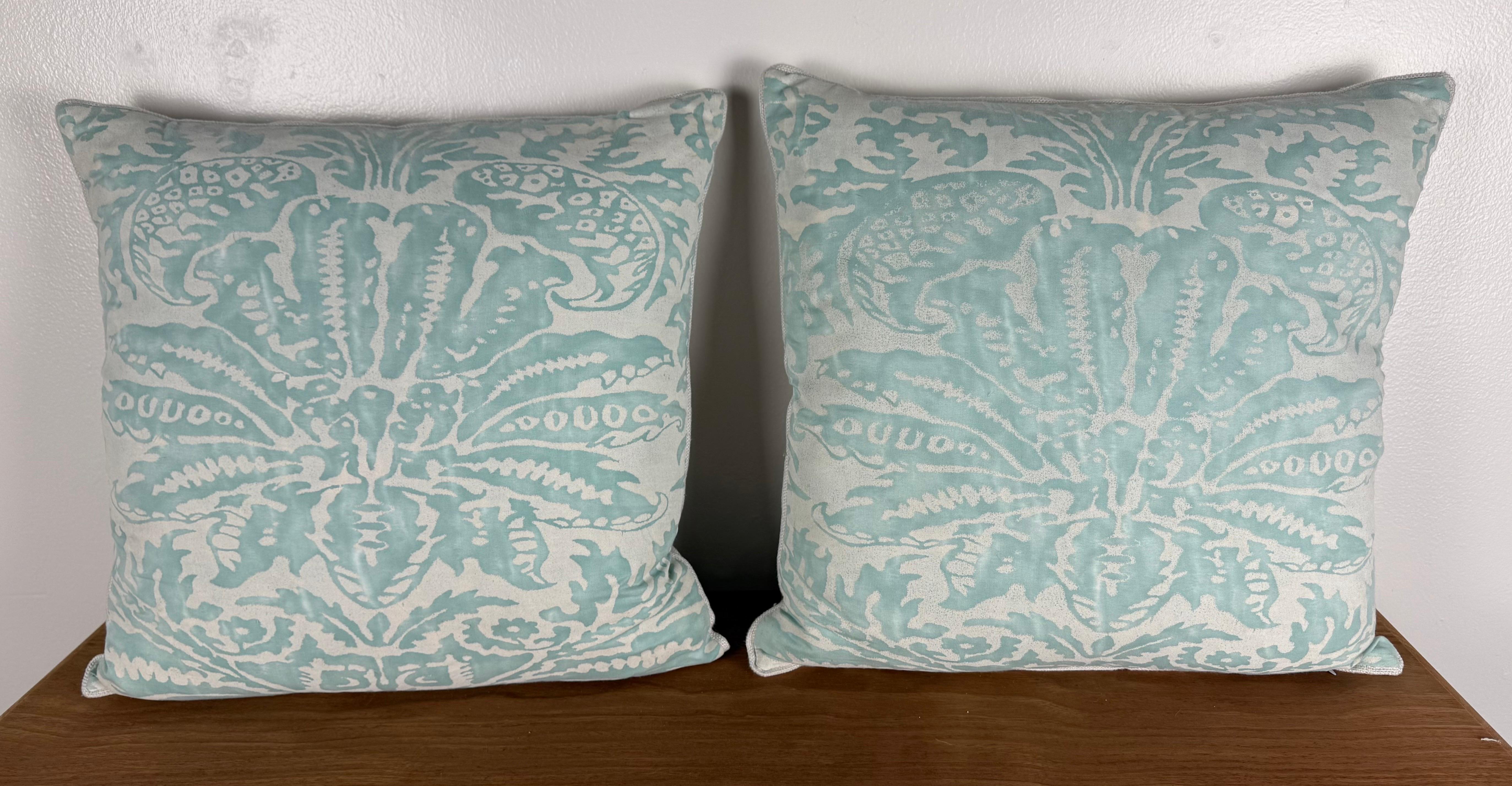 Une paire de coussins frais et élégants fabriqués à partir d'un textile de coton inspiré de Fortuny, présentant un motif damassé à grande échelle dans des tons doux d'aqua et de blanc. Le motif présente l'aspect classique de l'impression à la main
