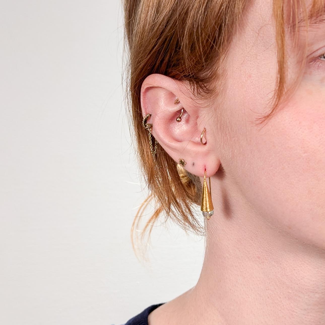 A very fine pair of high-karat gold and emerald ARA earrings.

With a wonderful Egyptian Revival or Ancient Mediterranean feel, the earrings consist of cone-shaped hand-hammered drops mounted with faceted rondelle-cut emerald beads.   

Marked ARA