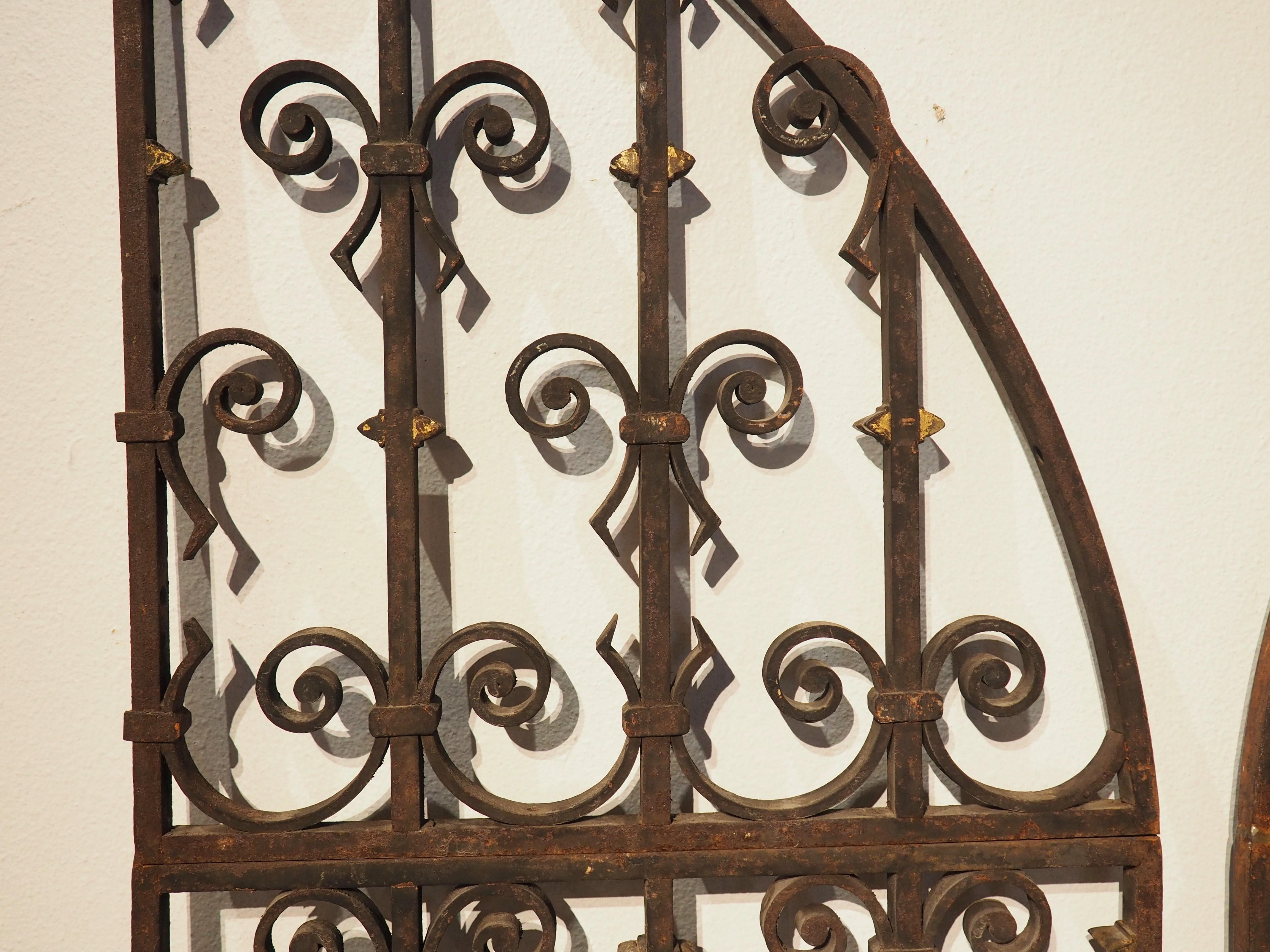 Recently removed from a French chateau, this pair of arched wrought iron gates was forged in the 1800’s. There are no modern welds on these gates, meaning that each piece of iron has been screwed, pegged, and banded together. The scrollwork is